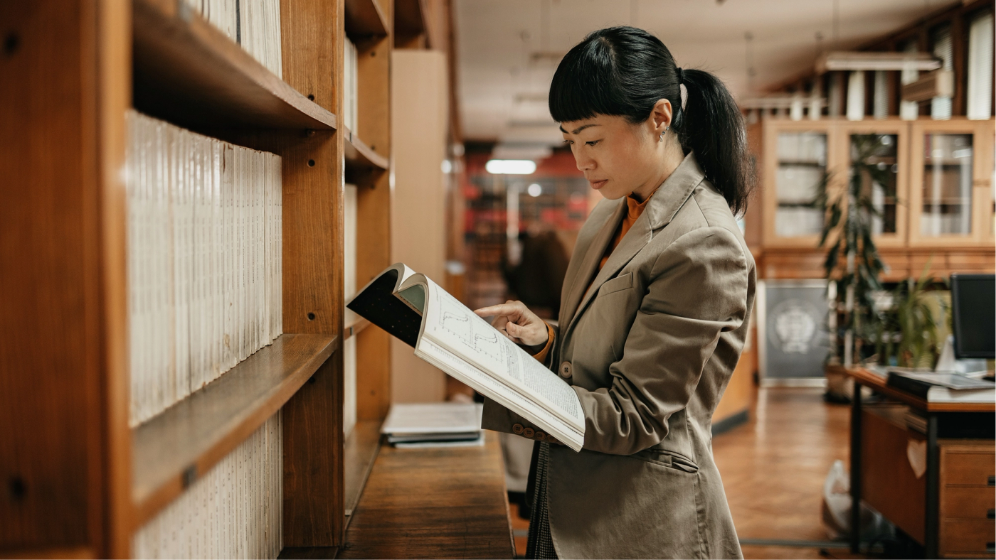 A researcher reviewing a journal in a library aisle
