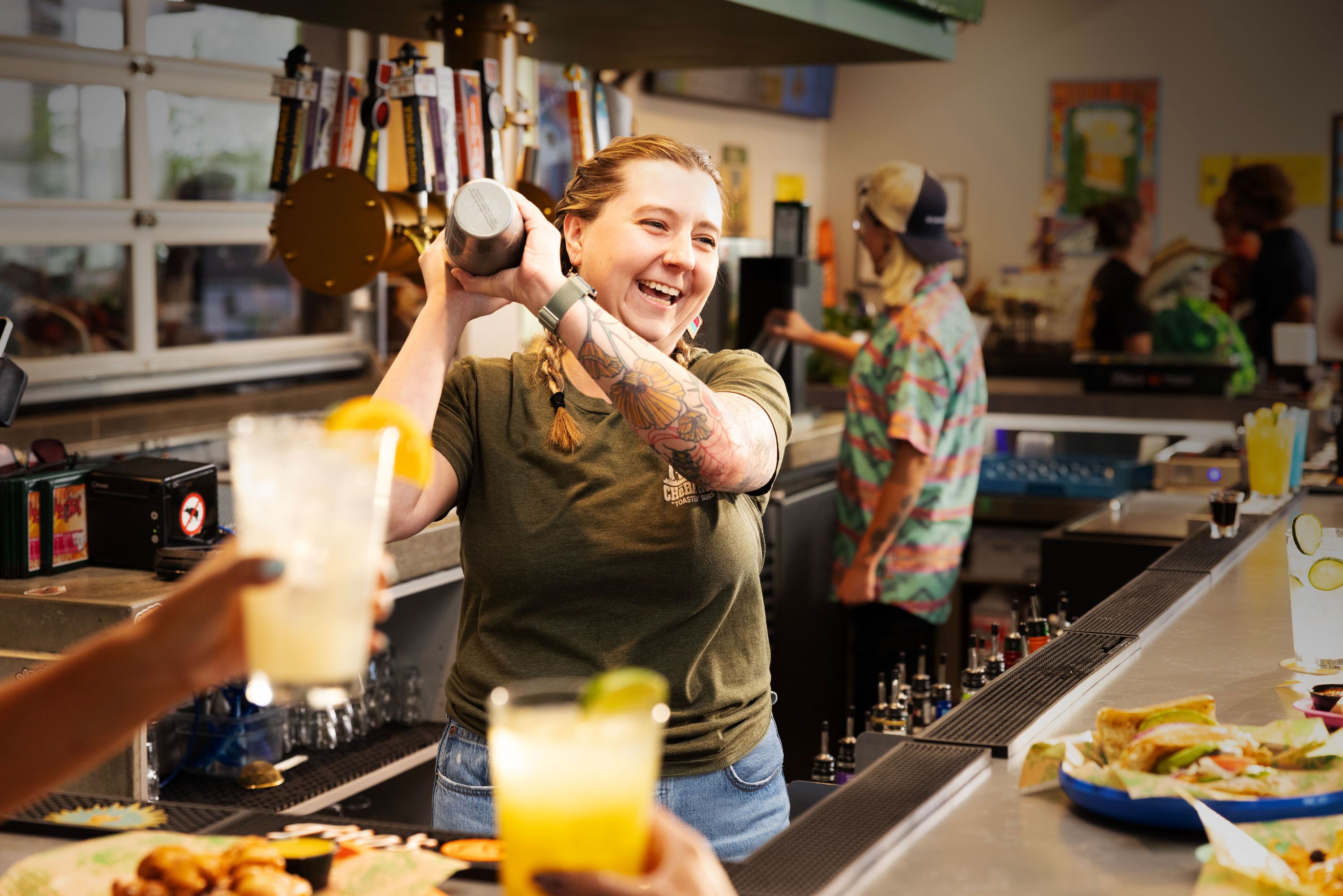 Bartender presenting an orange cocktail at a bar