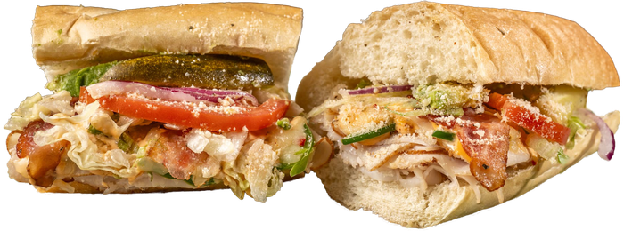 Two loaded toasted subs with vegetables, pickles, and creamy sauce