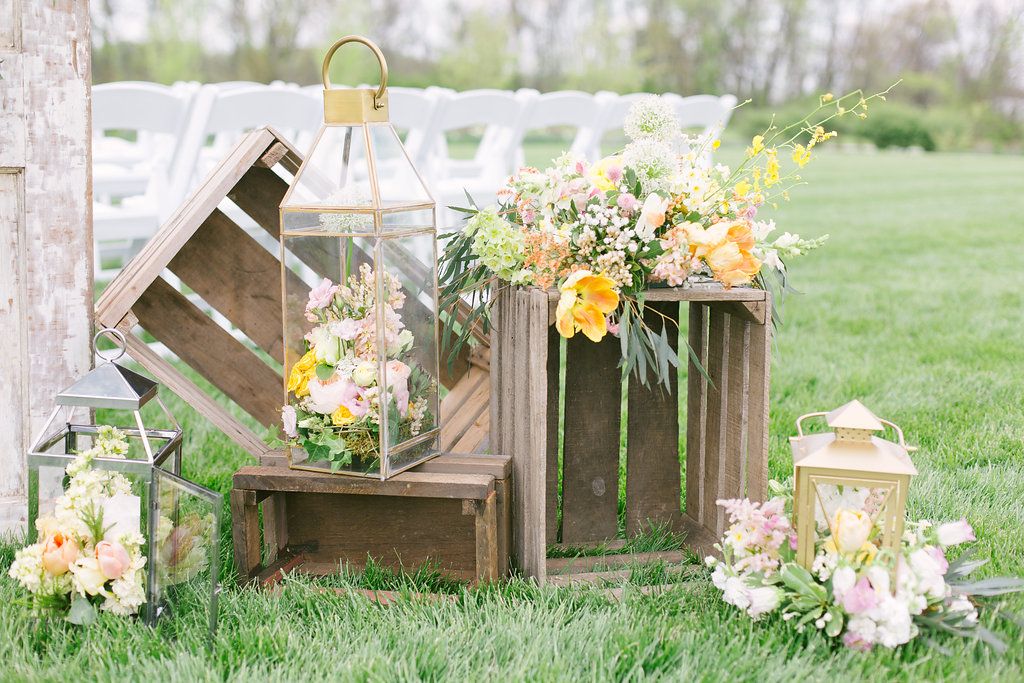 vintage crates and lanterns filled with flowers and an accent arrangement of yellow, white, pink and peach flowers