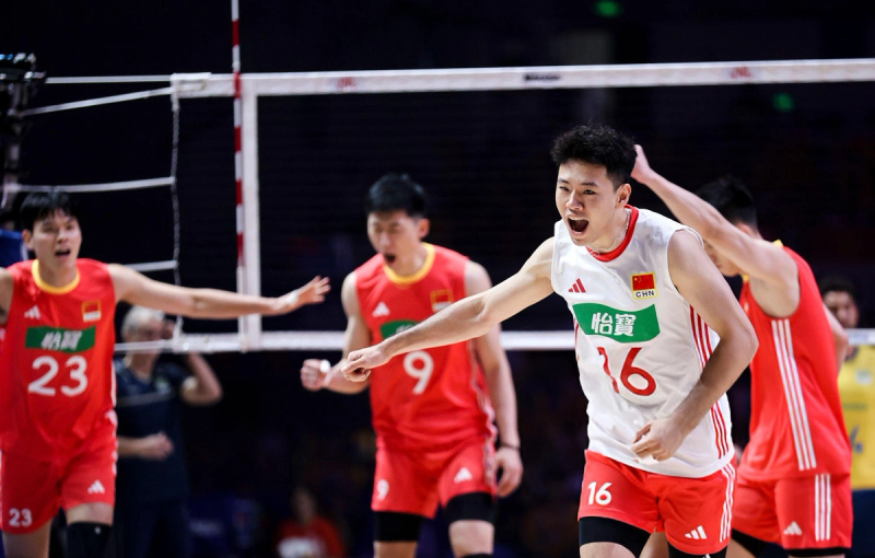 Volleyball players in red and white jerseys celebrate a point on the court, showing expressions of excitement and triumph.