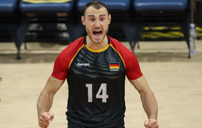 A volleyball player in a Germany jersey with number 14 is celebrating passionately on the court.
