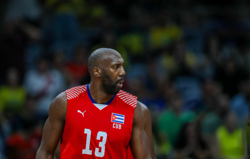 Basketball player in a red Cuban jersey with number 13, looking to the side during a game.