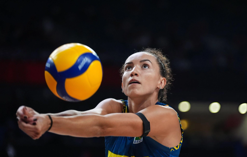 A volleyball player focused on receiving a ball during a game, wearing a blue and yellow uniform.