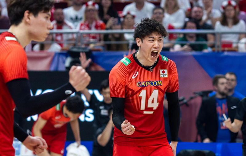 A volleyball player in a red and orange jersey, number 14, is cheering energetically on the court.
