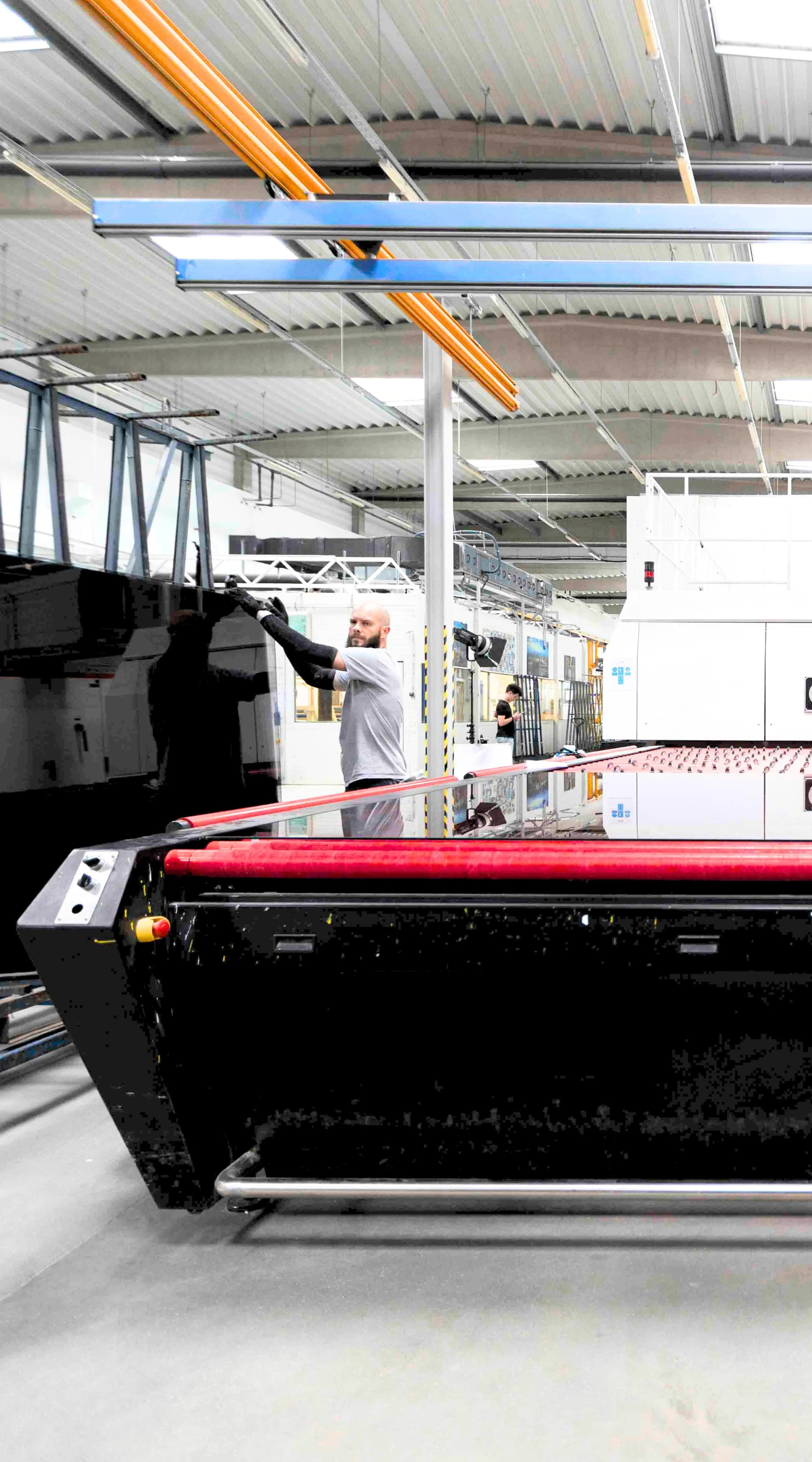 Two men operate a machine for making tempered glass