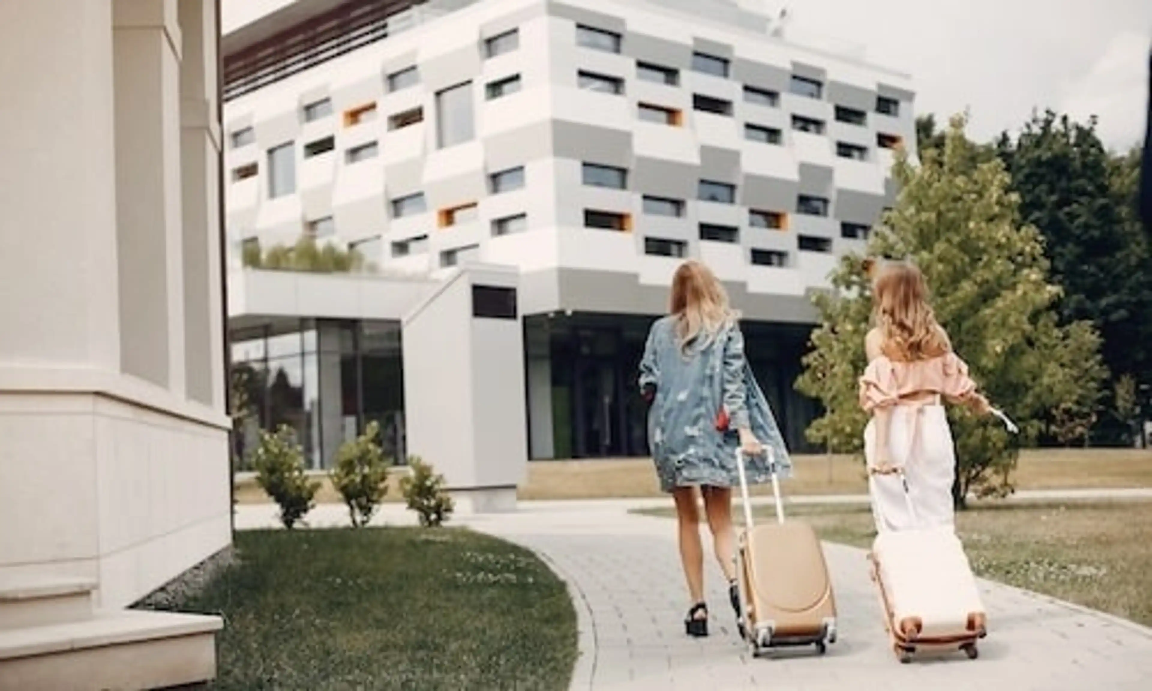 Two ladies are pulling suitcases on the sidewalk