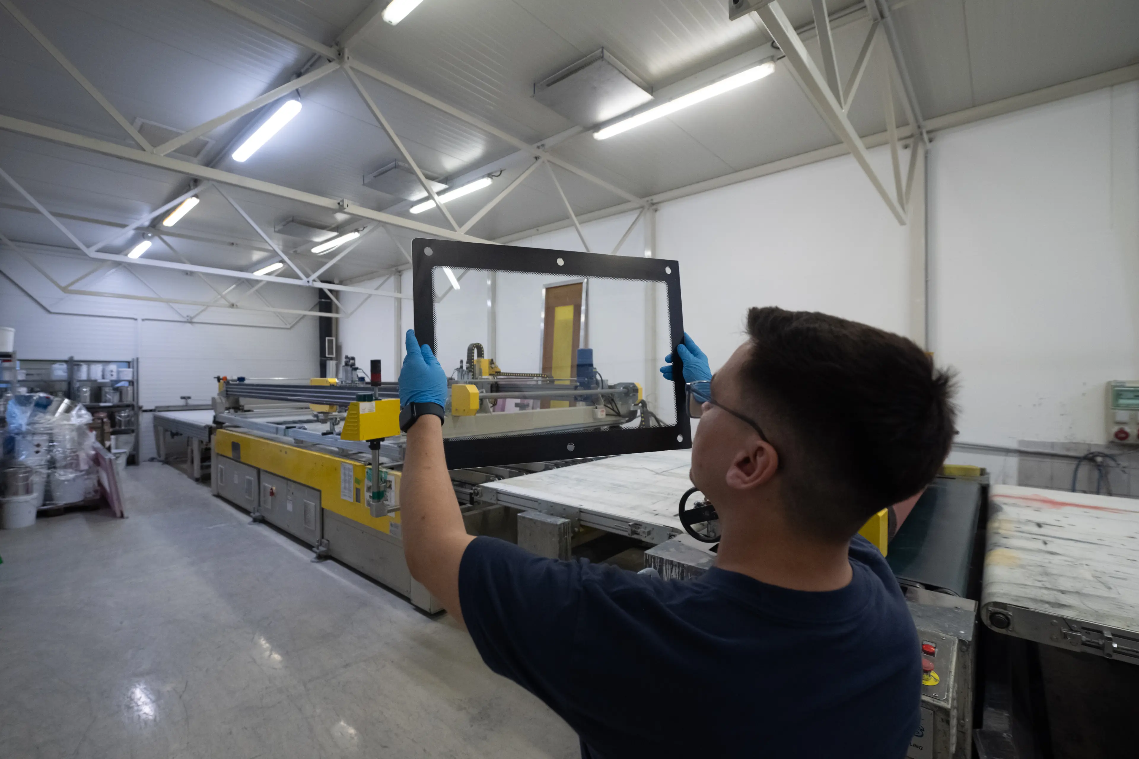 A man is inspecting a piece of glass