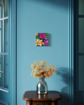small painting of flowers against a blue wall above a dried flower arrangement