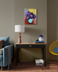 Painting of purple flowers hung above a small table with lamp