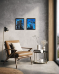 Two paintings hung on a gray wall behind a chair and lamp.