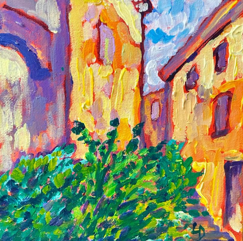 Sunny alley between buildings with a bush in the foreground