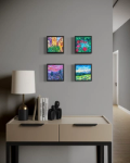 Four small paintings above a desk with lamp and books