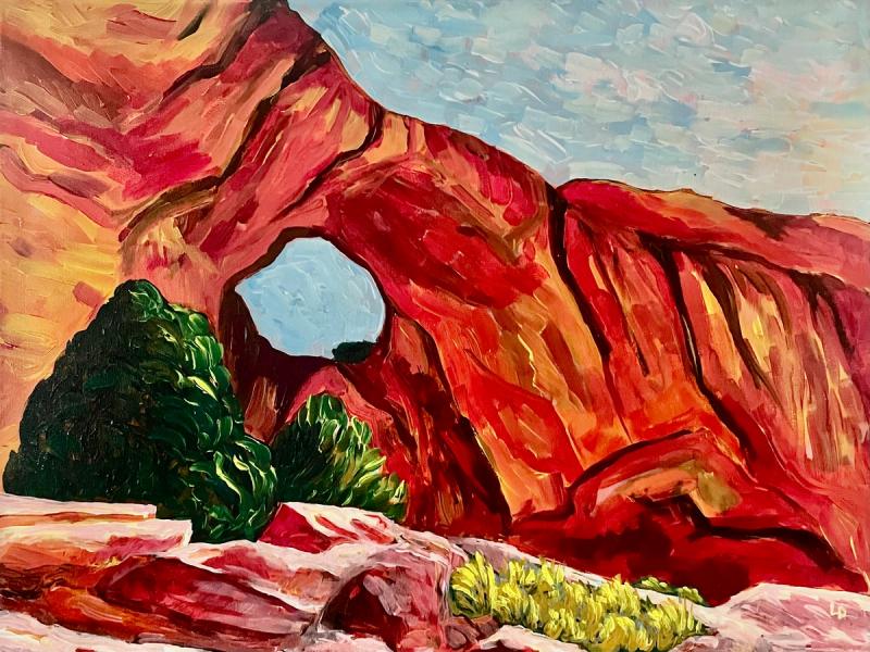 A red sandstone arch with juniper trees in the foreground that the sky showing above and through the arch