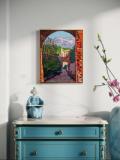 Painting of rustic village viewed through stone arch on wall above dresser