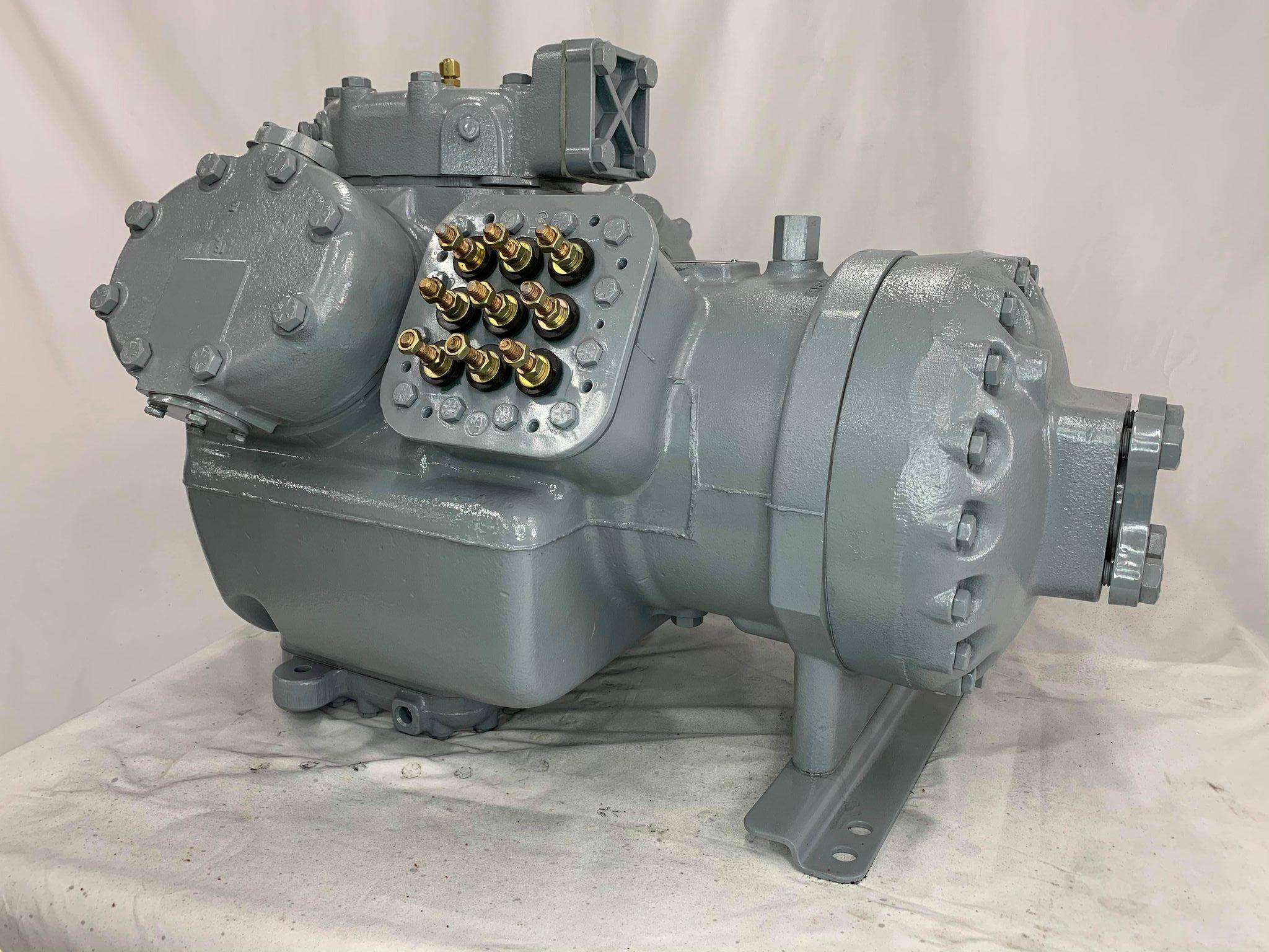 Remanufactured Carrier 06E semi-hermetic reciprocating compressor with visible fittings and mounting feet.