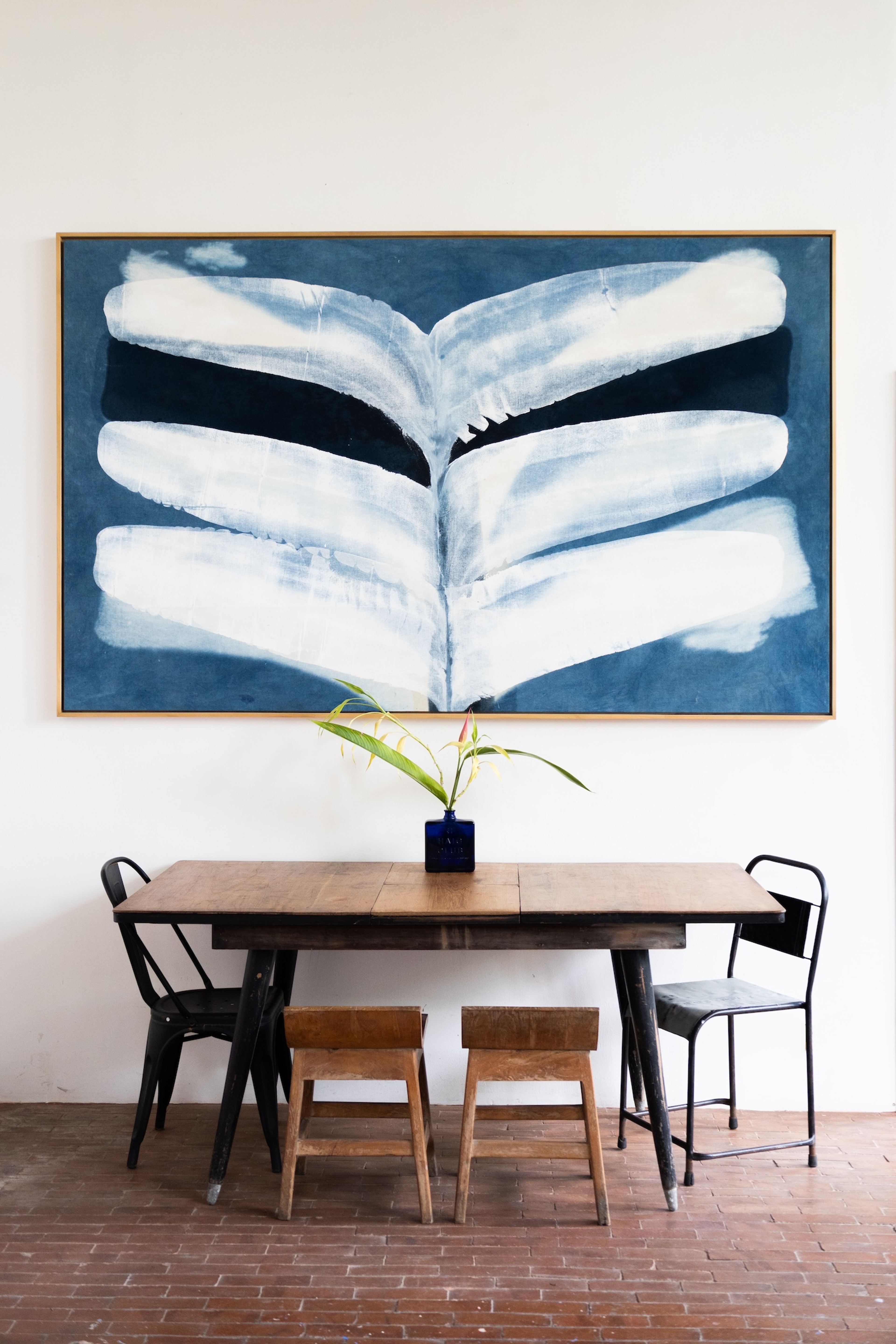 Abstract indigo painting with flowing organic forms by Jake Paul White, natural pigment on canvas, hung above a dinning room table