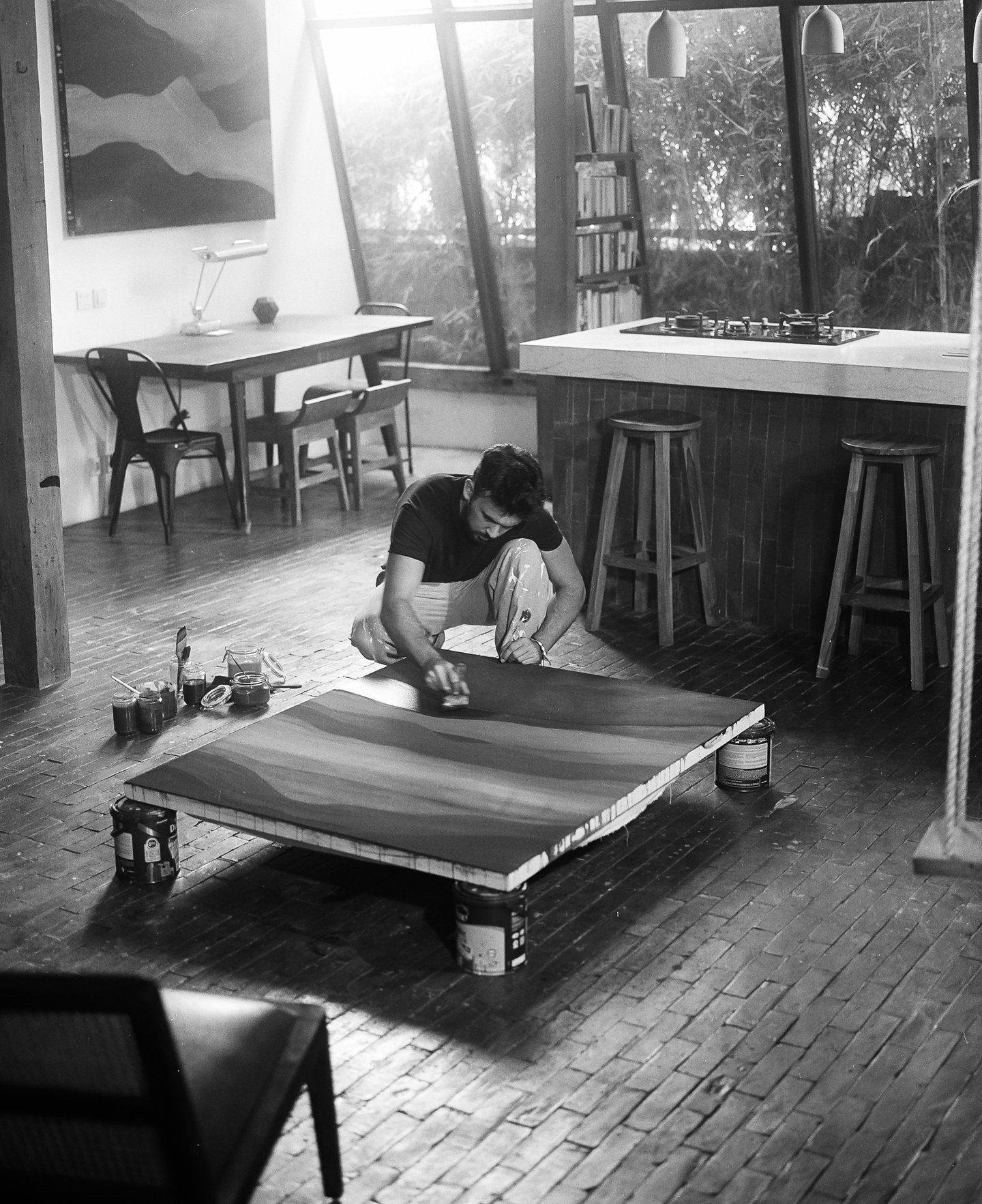 Artist painting a large scale abstract artwork on the floor inside a light filled studio.