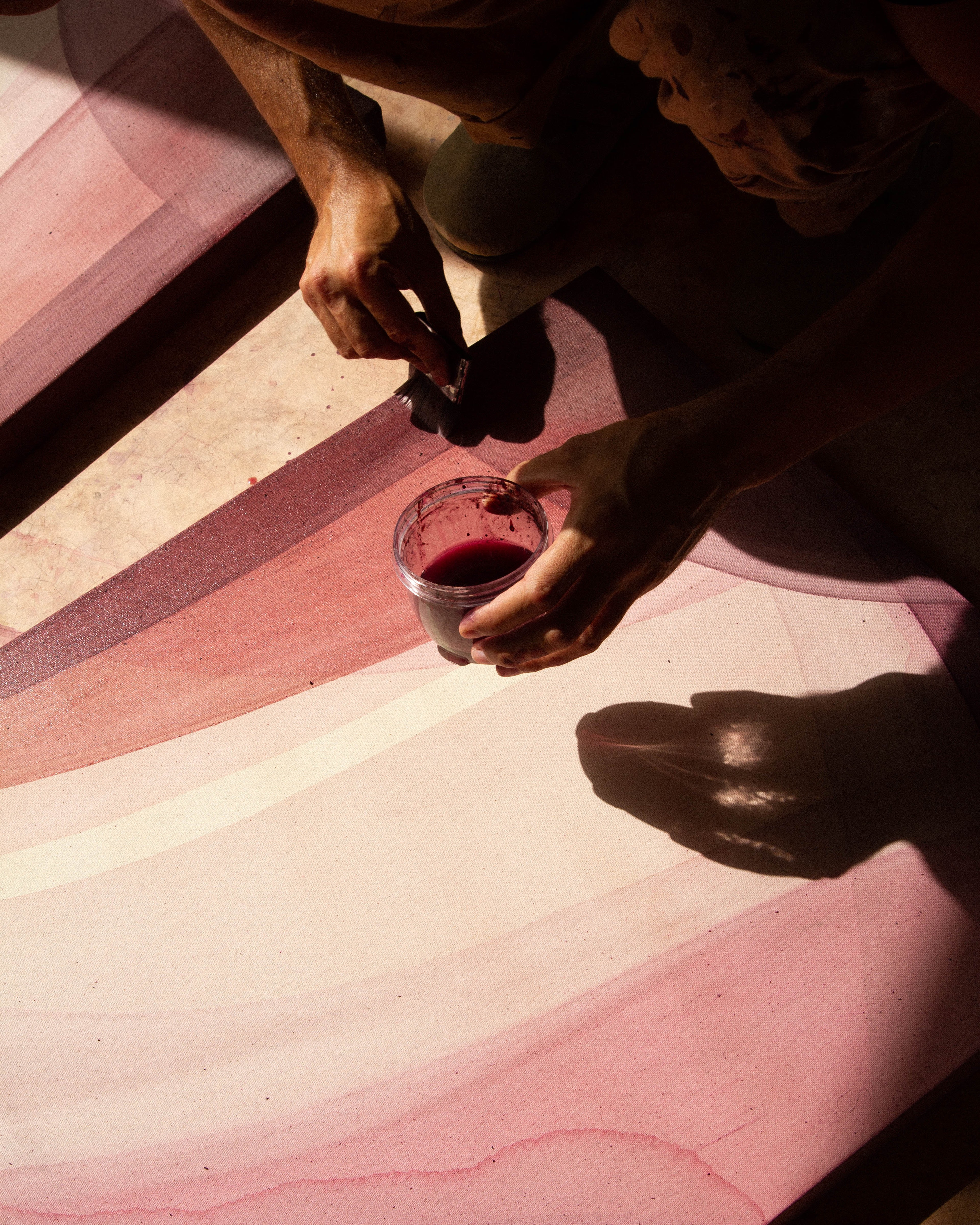 An artist applying pigment to a canvas while working on an abstract painting in the studio.