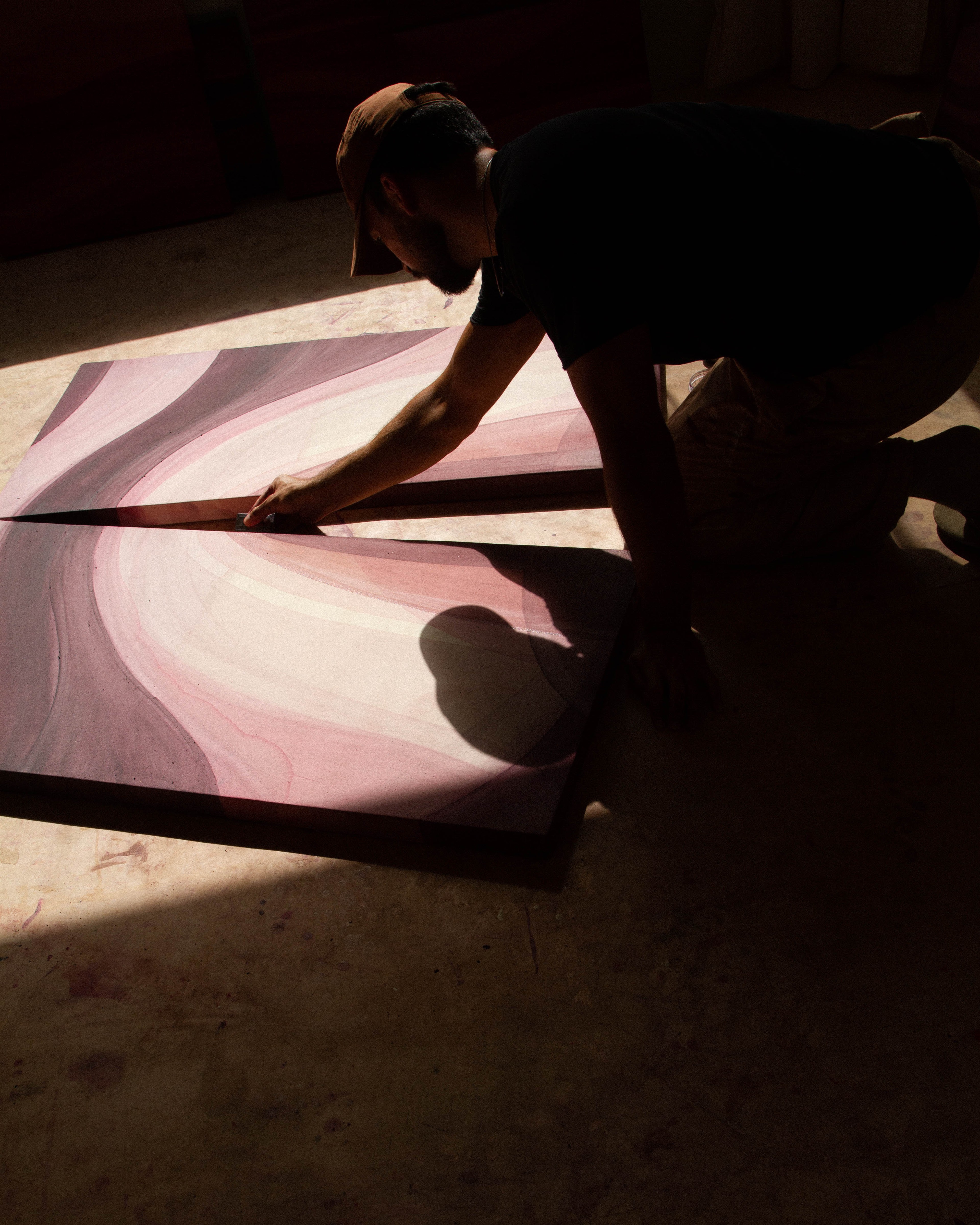 An artist applying natural pigment to a canvas while working on an abstract painting in the studio.