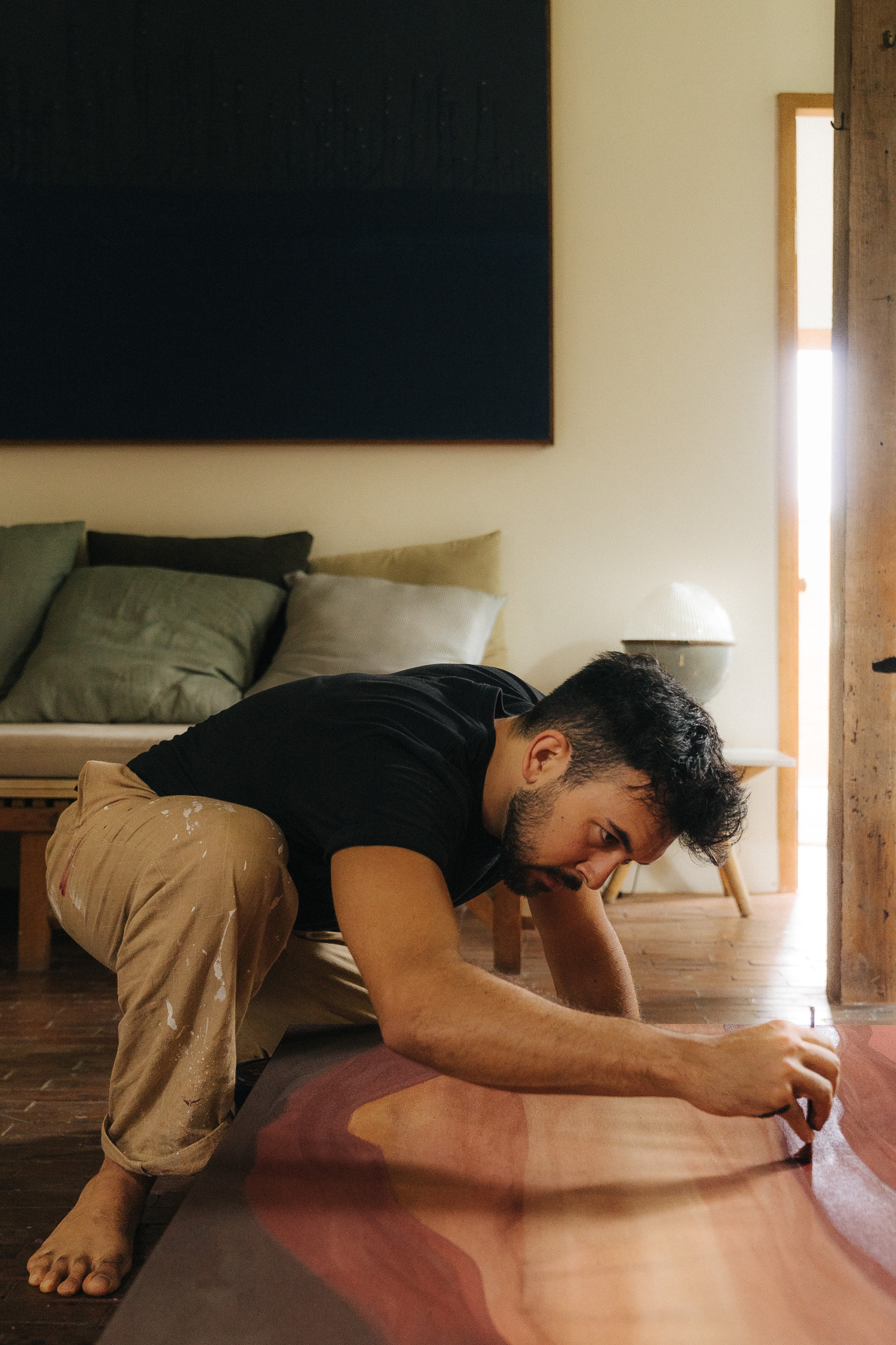 Jake Paul White painting an abstract red clay painting with natural dyes and pigments on canvas, close up, in his Bali artist studio