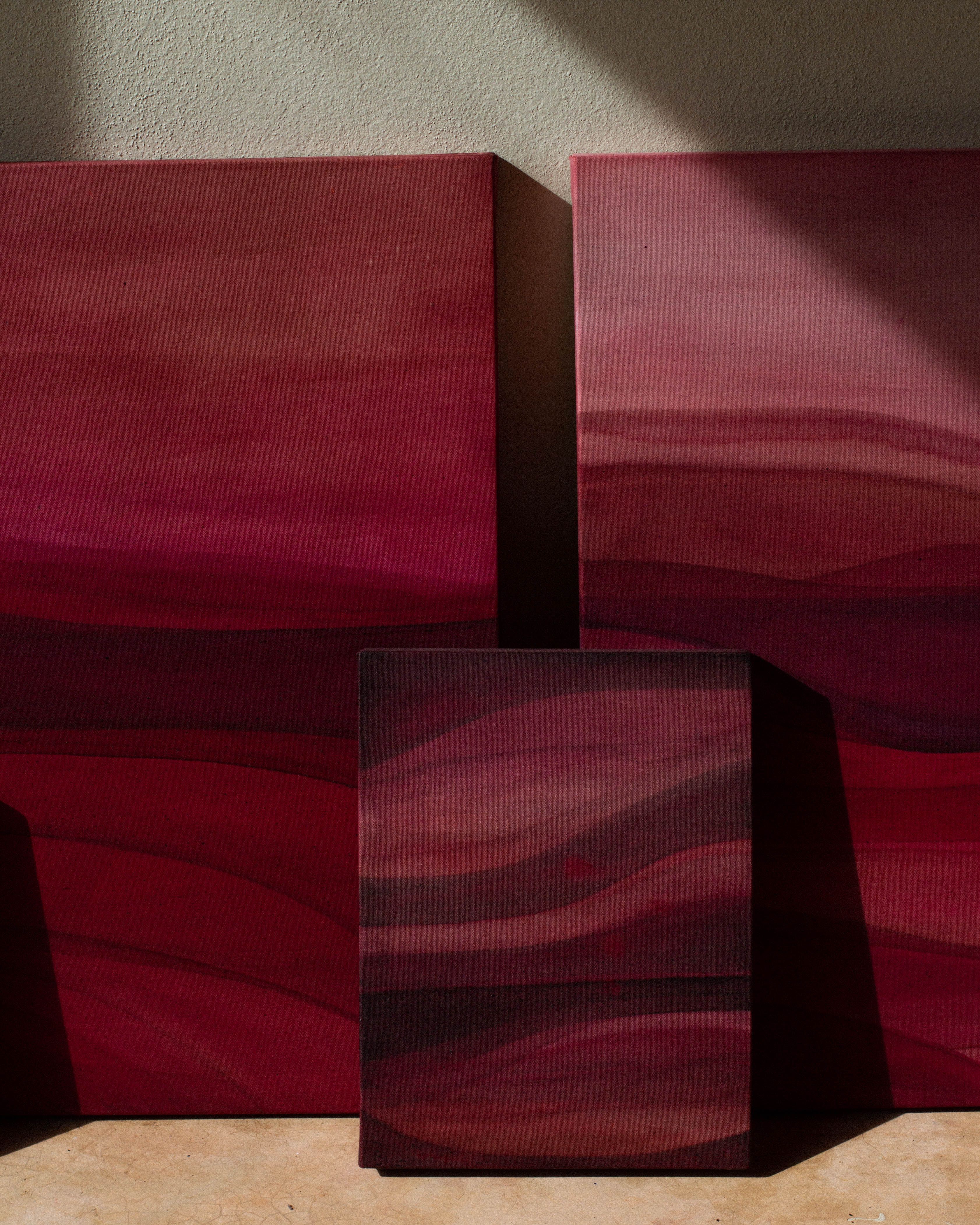 Abstract paintings stacked against a wall in warm natural light on the studio floor.