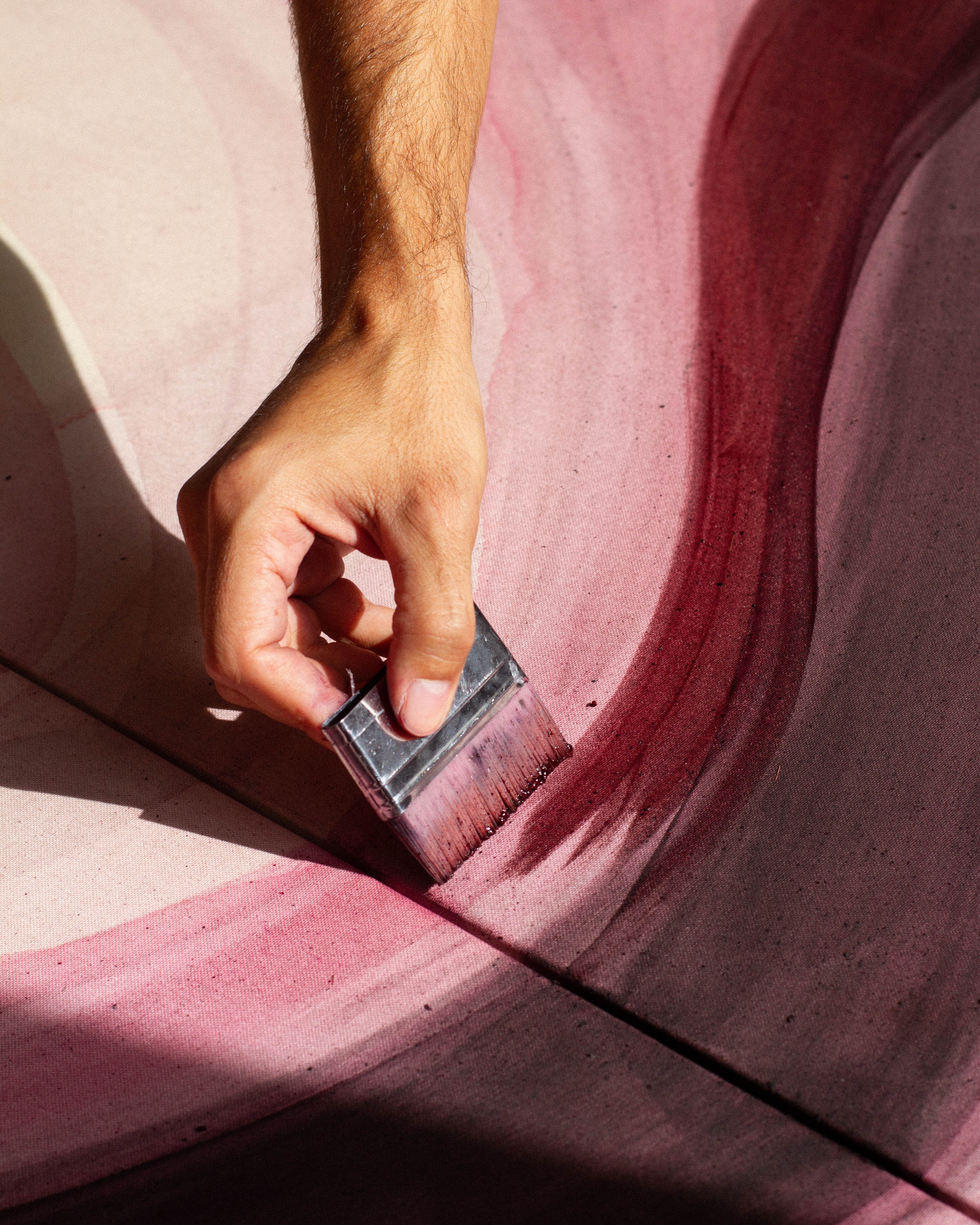 An artist applying pigment to a canvas while working on an abstract painting in the studio.