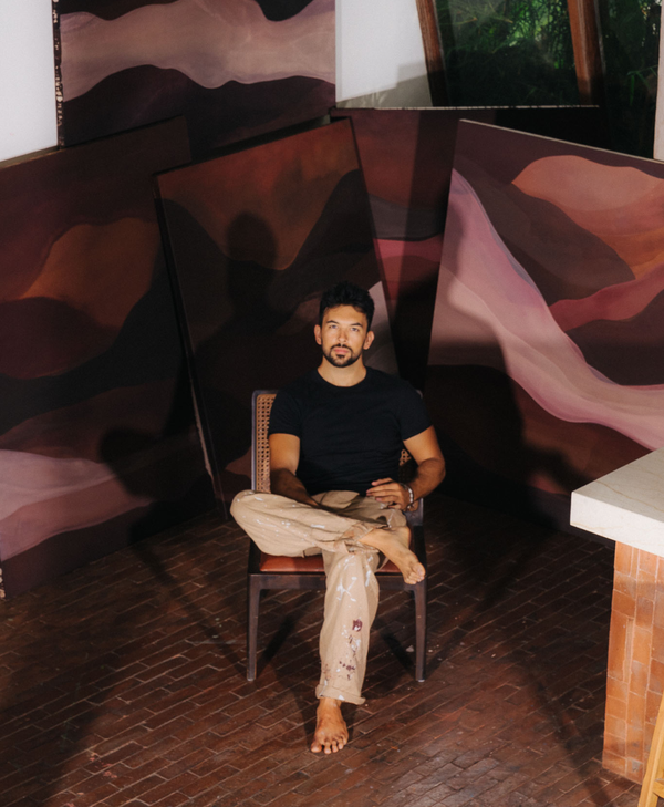 Jake Paul White sitting infront of his abstract natural paintings, in his Bali artist studio
