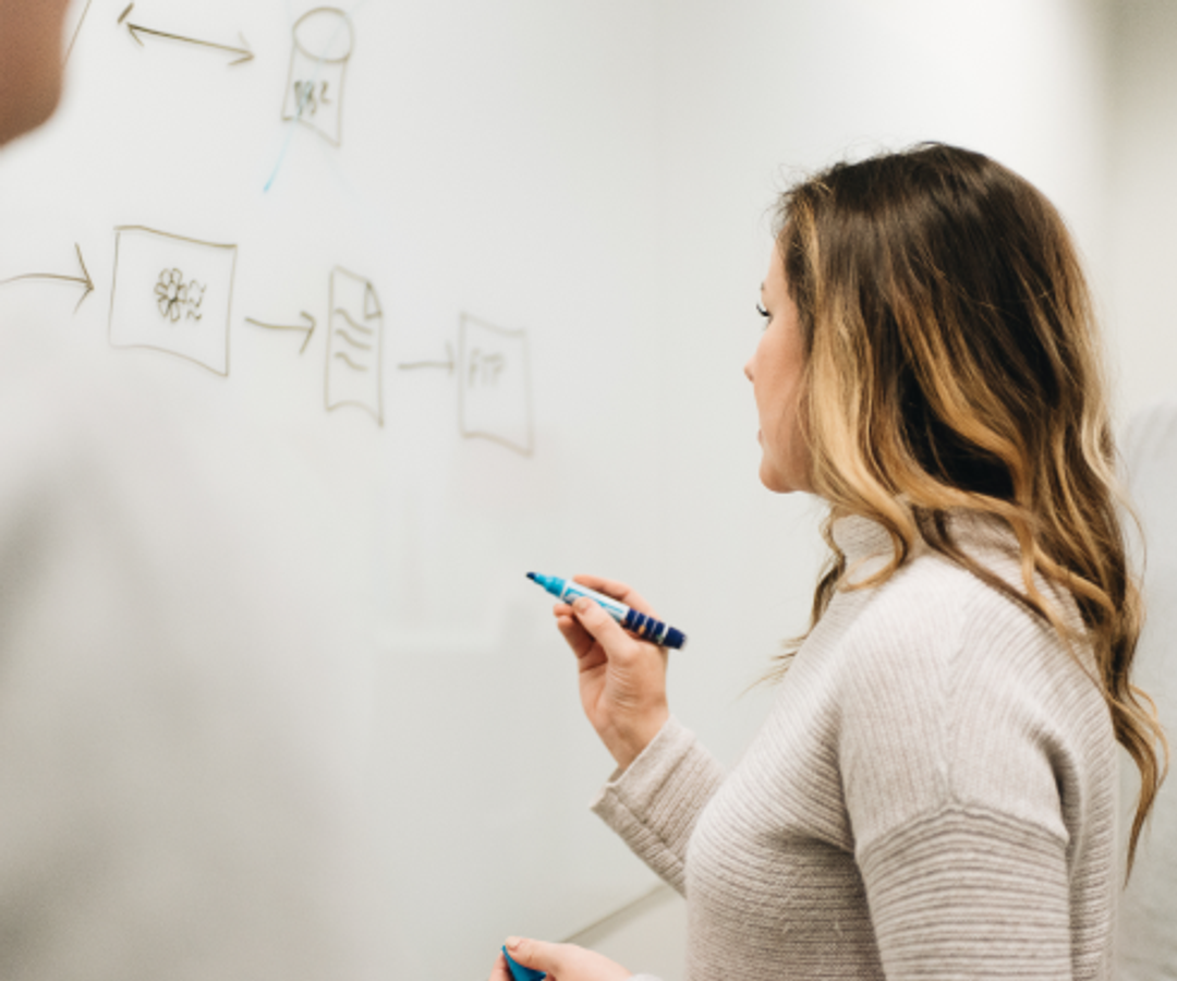 Woman writing on a whiteboard with a blue marker