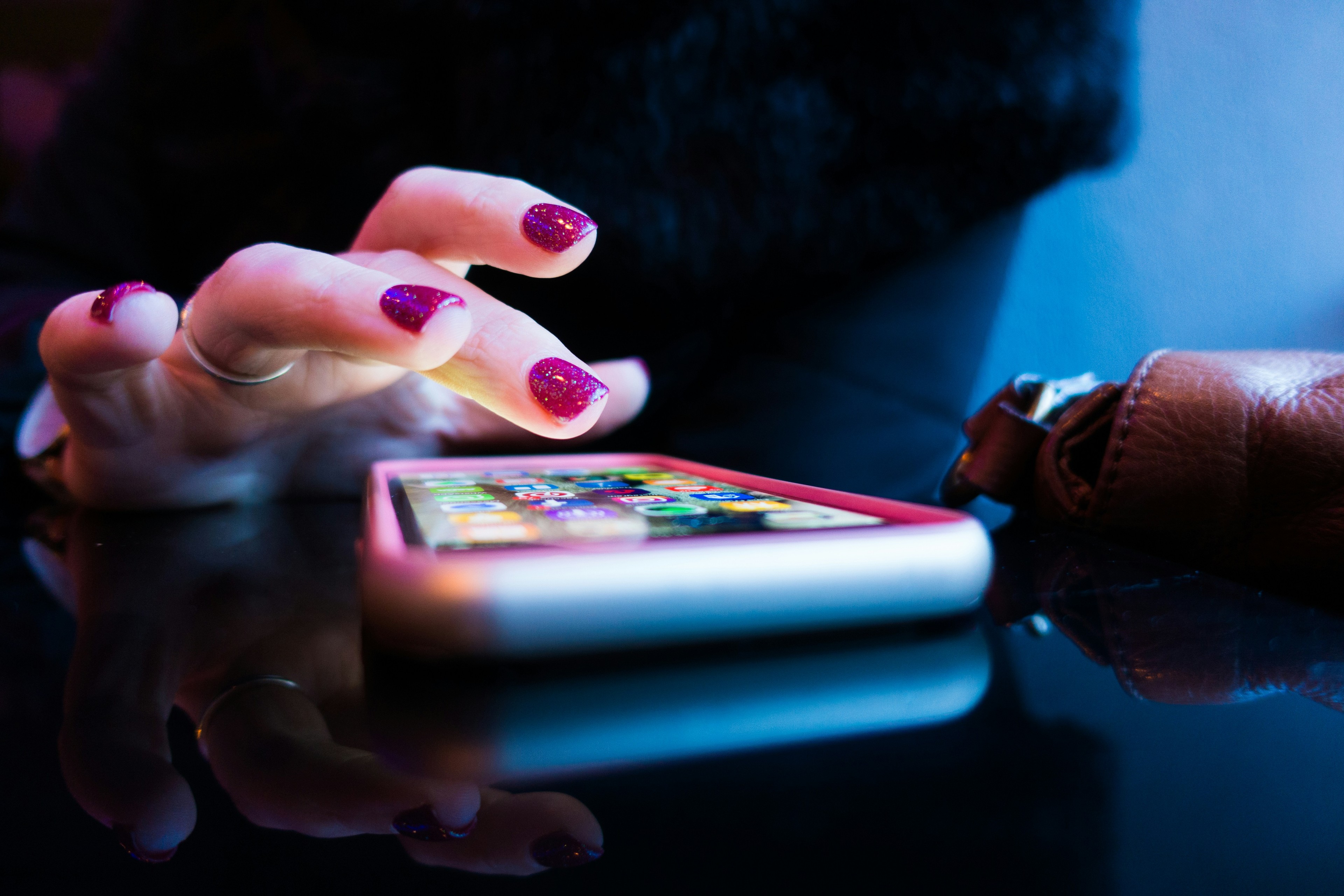 Person using their phone with pink fingernail paint