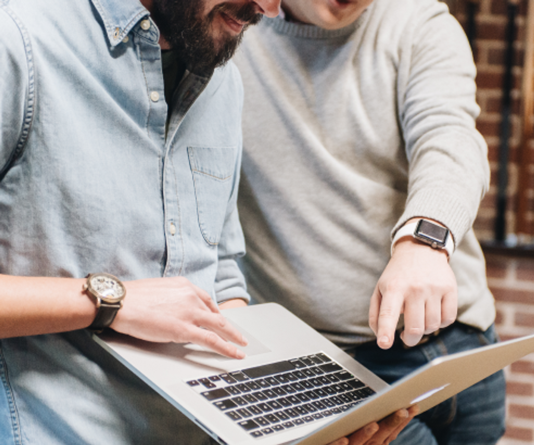 Man pointing to a laptop held by another man