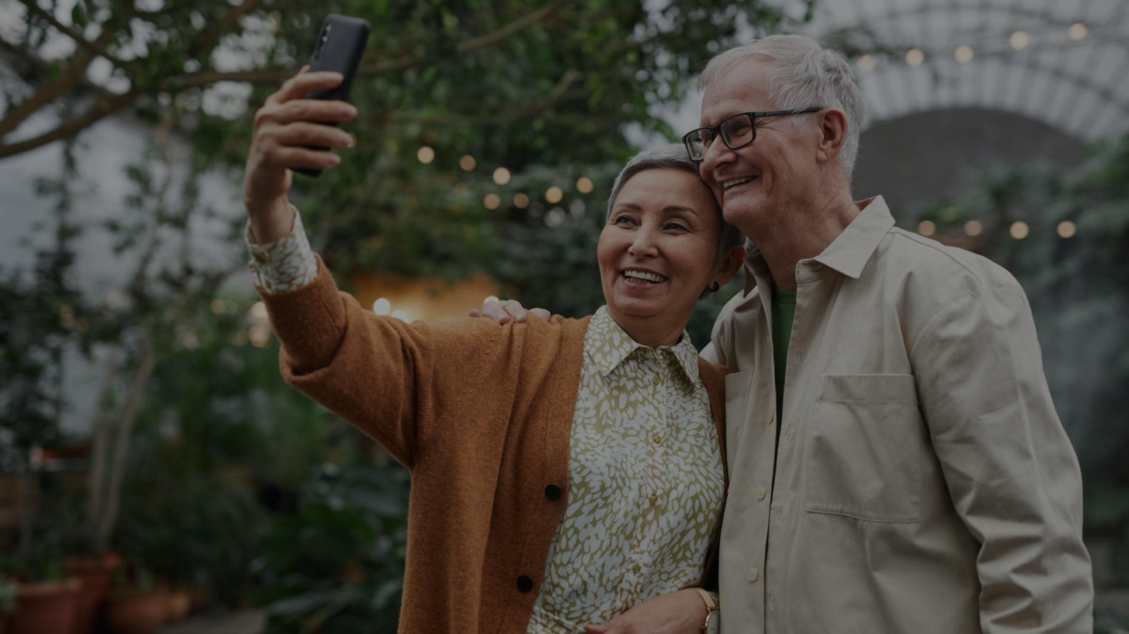 Two elderly people smiling at a smartphone camera