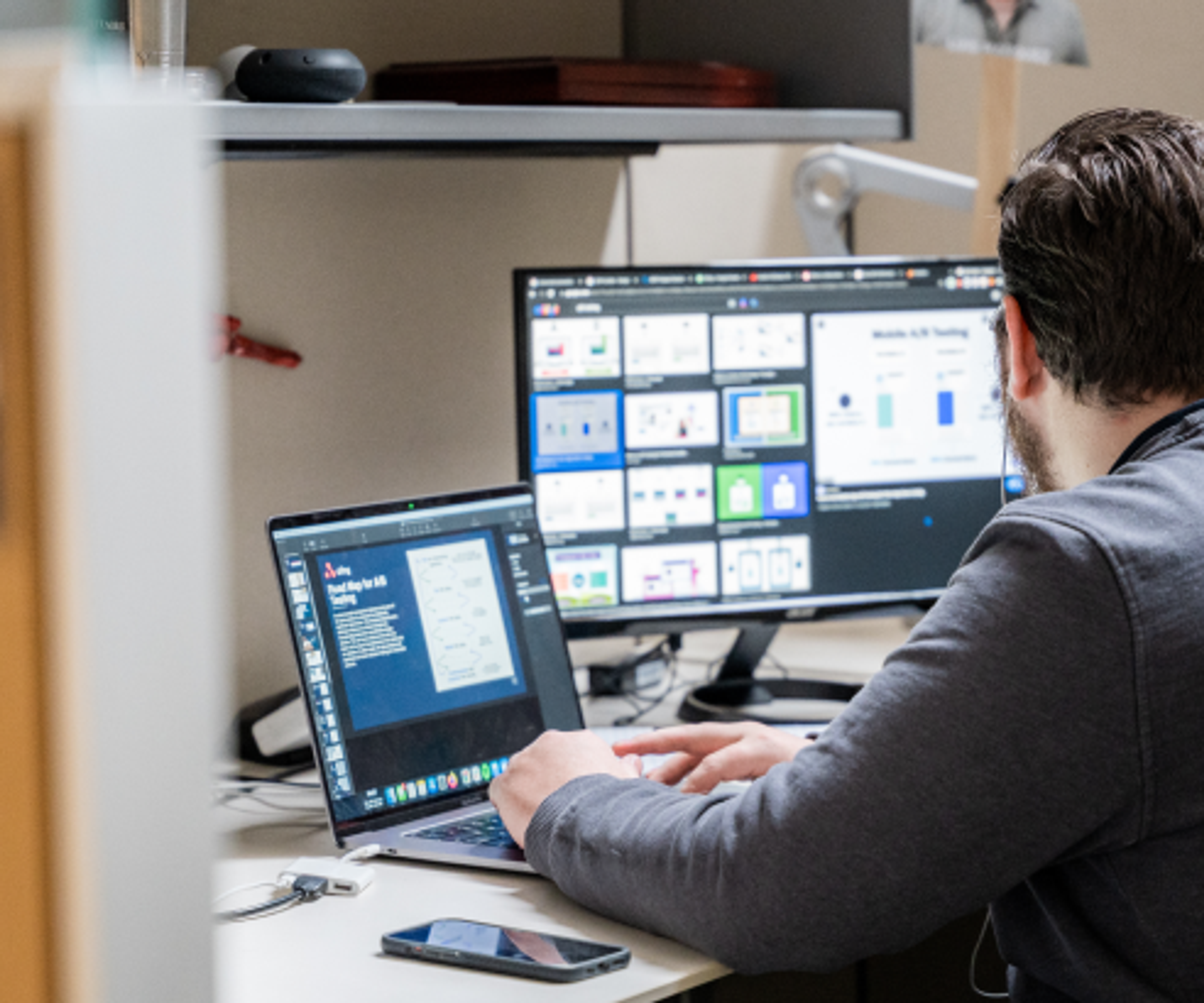 Man using a laptop while looking at a desktop monitor