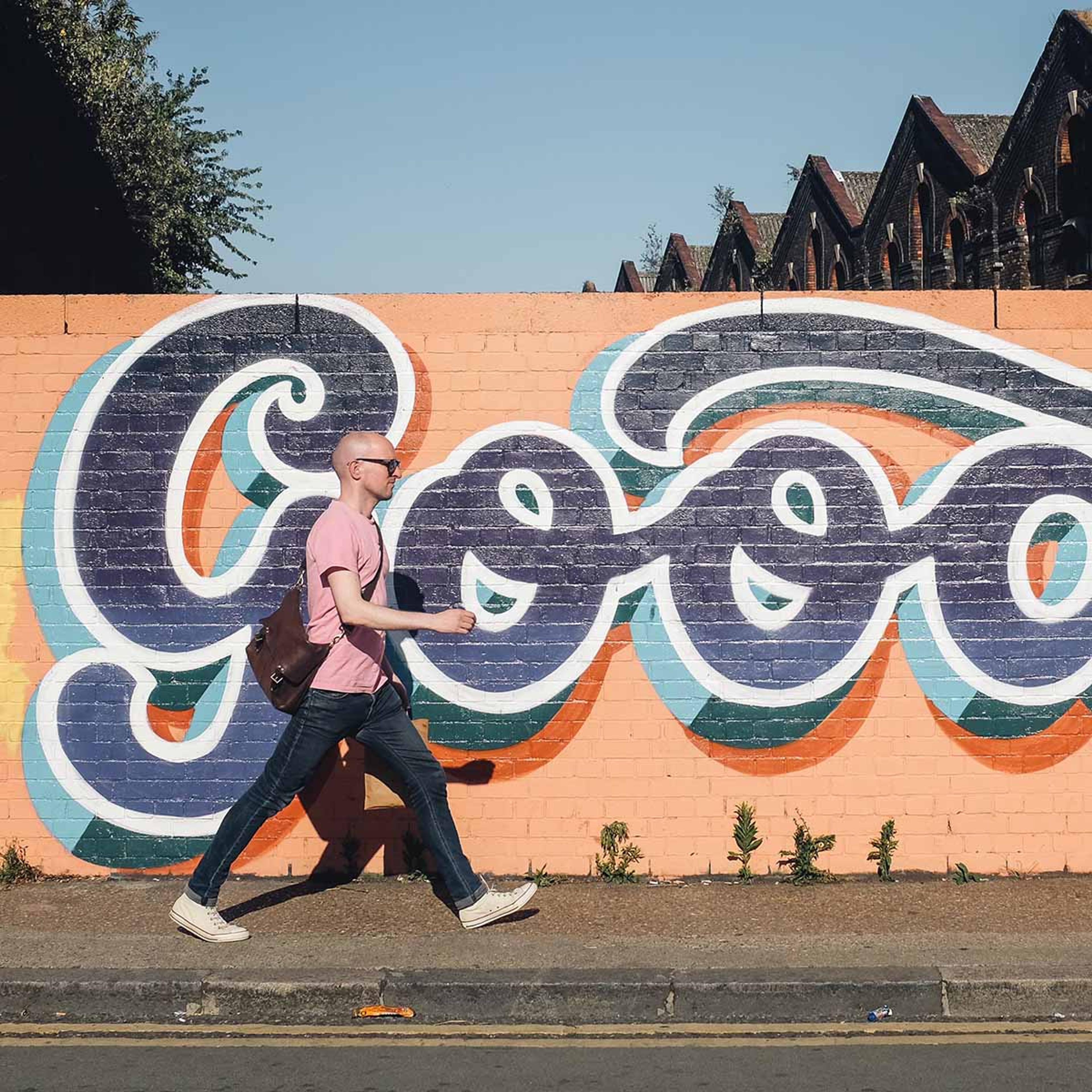 Man walking past a mural on the sidewalk