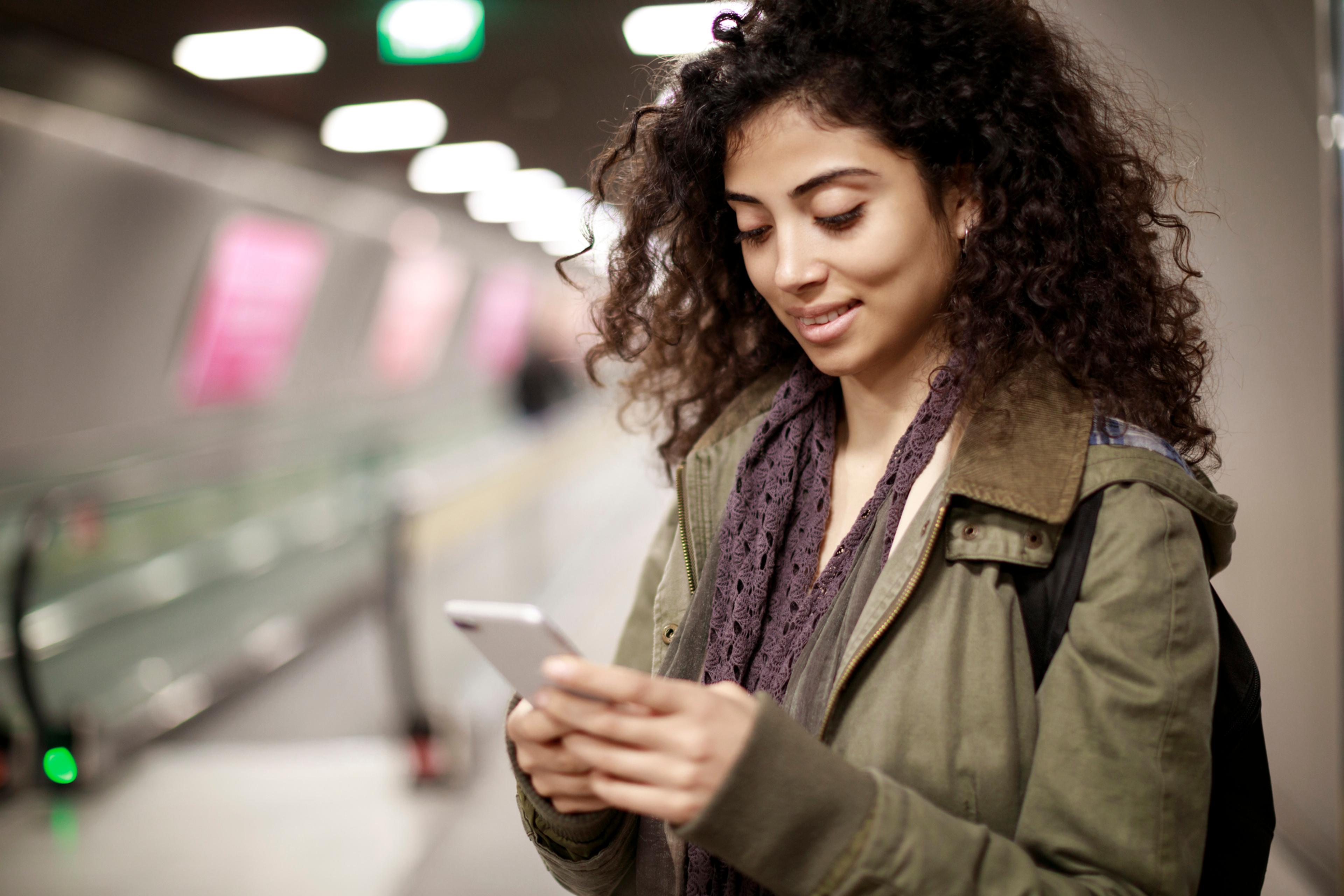 Woman smiling at her phone in a subway station