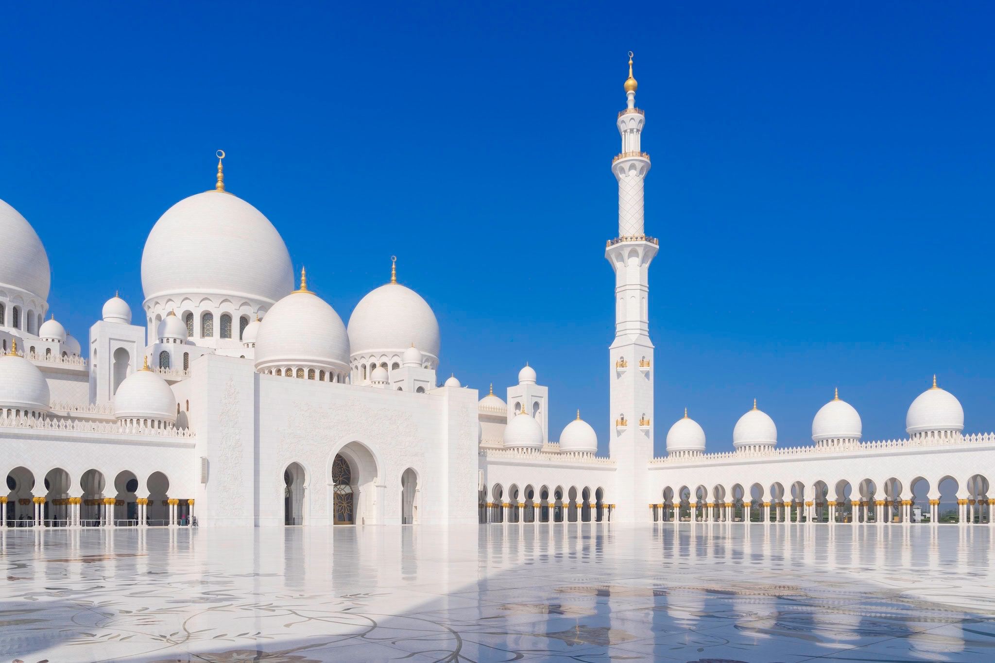June: The white marble courtyard and domes of the grand mosque, Abu Dhabi, United Arab Emirates