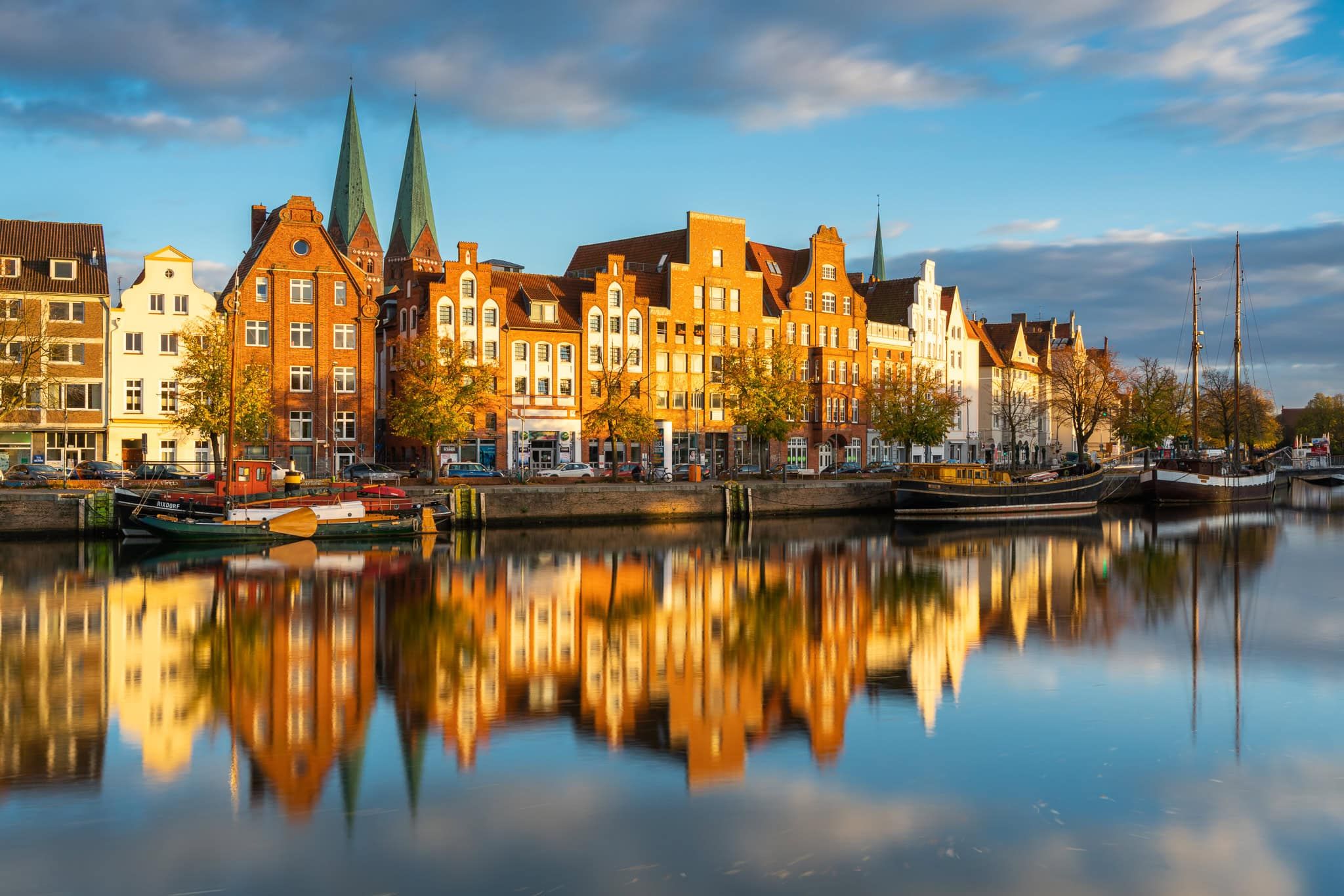 Colorful merchant houses reflected in Trave River with St. Marienkirche towers, Lübeck, Germany