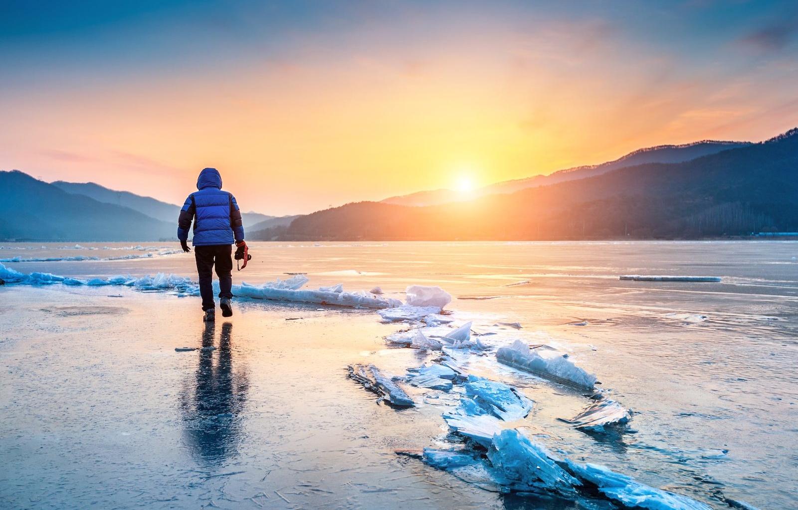 Photographer on frozen lake at sunrise