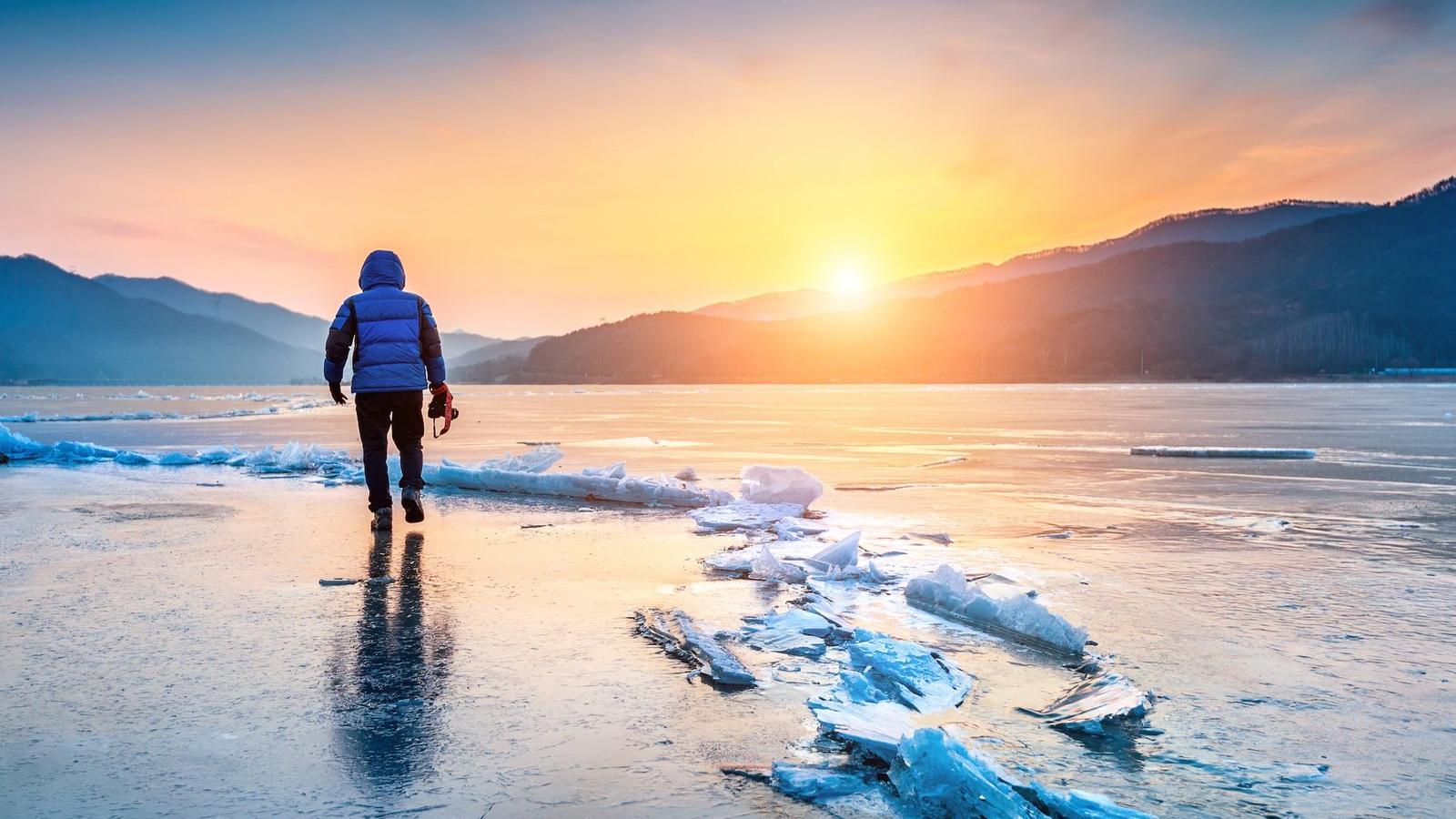Photographer on frozen lake at sunrise