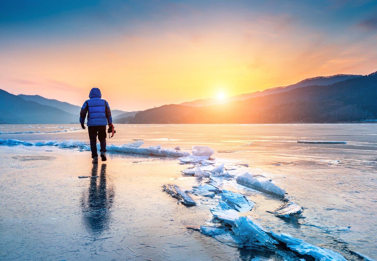 Photographer on frozen lake at sunrise