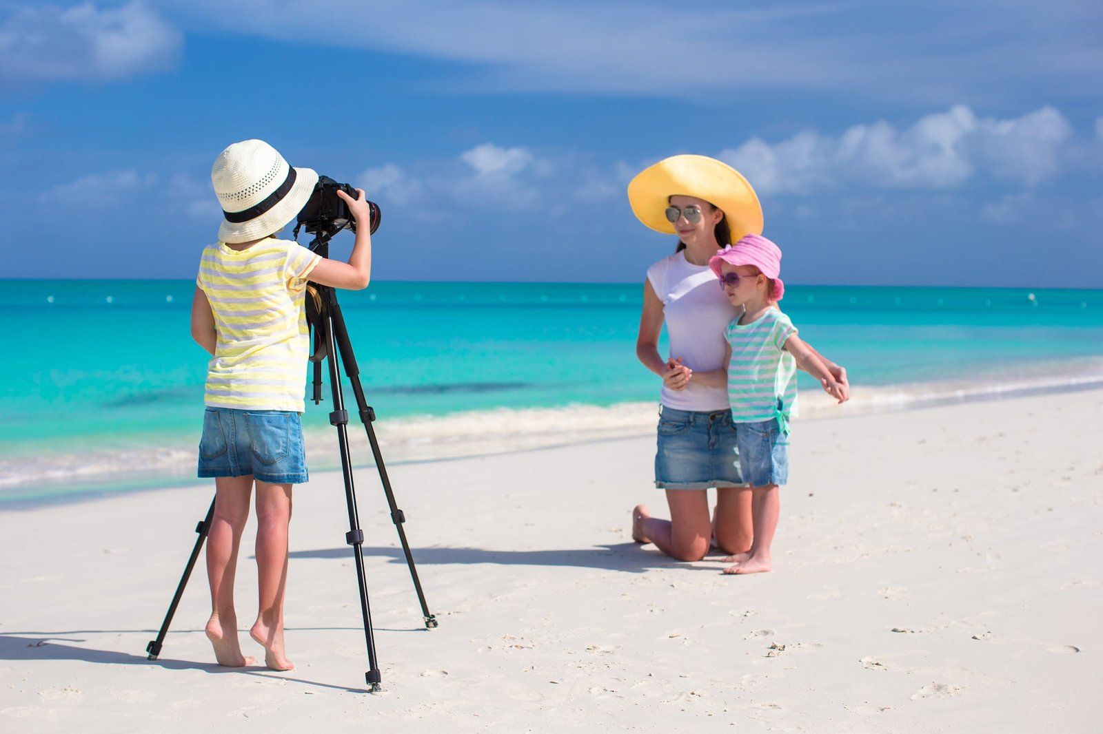 Family taking photos on tropical beach with turquoise water, Maldives