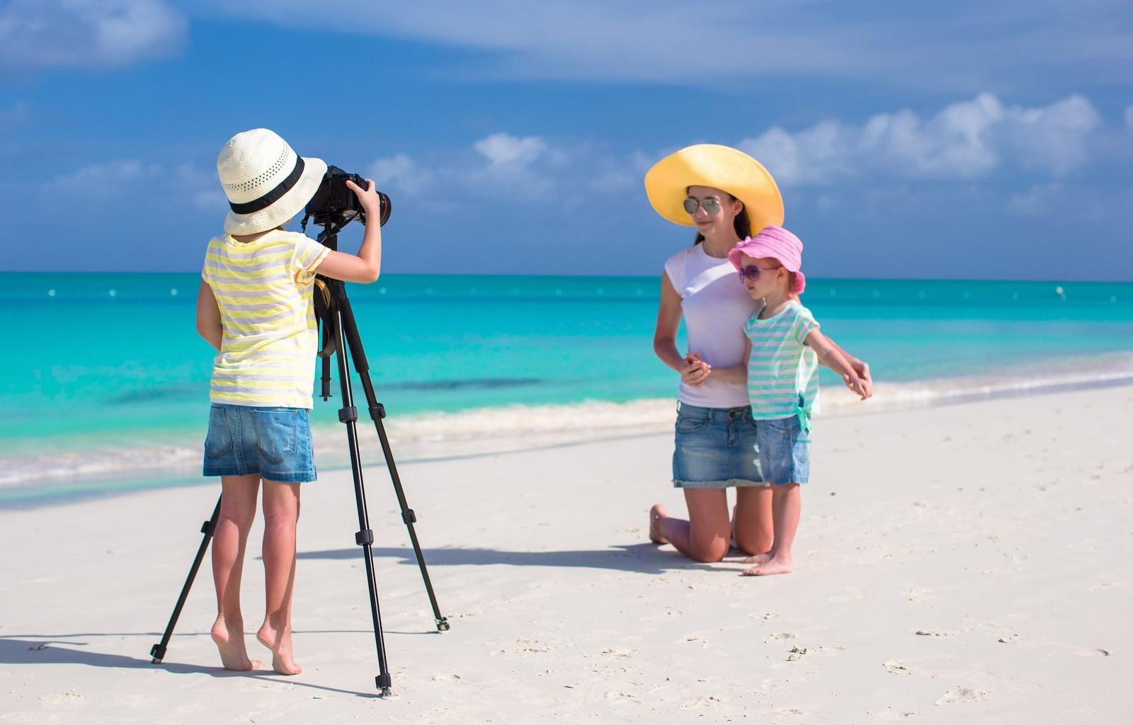 Family taking photos on tropical beach with turquoise water, Maldives