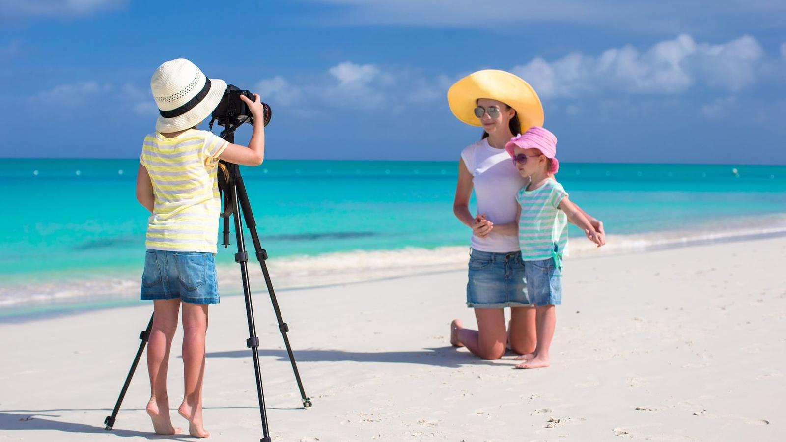 Family taking photos on tropical beach with turquoise water, Maldives