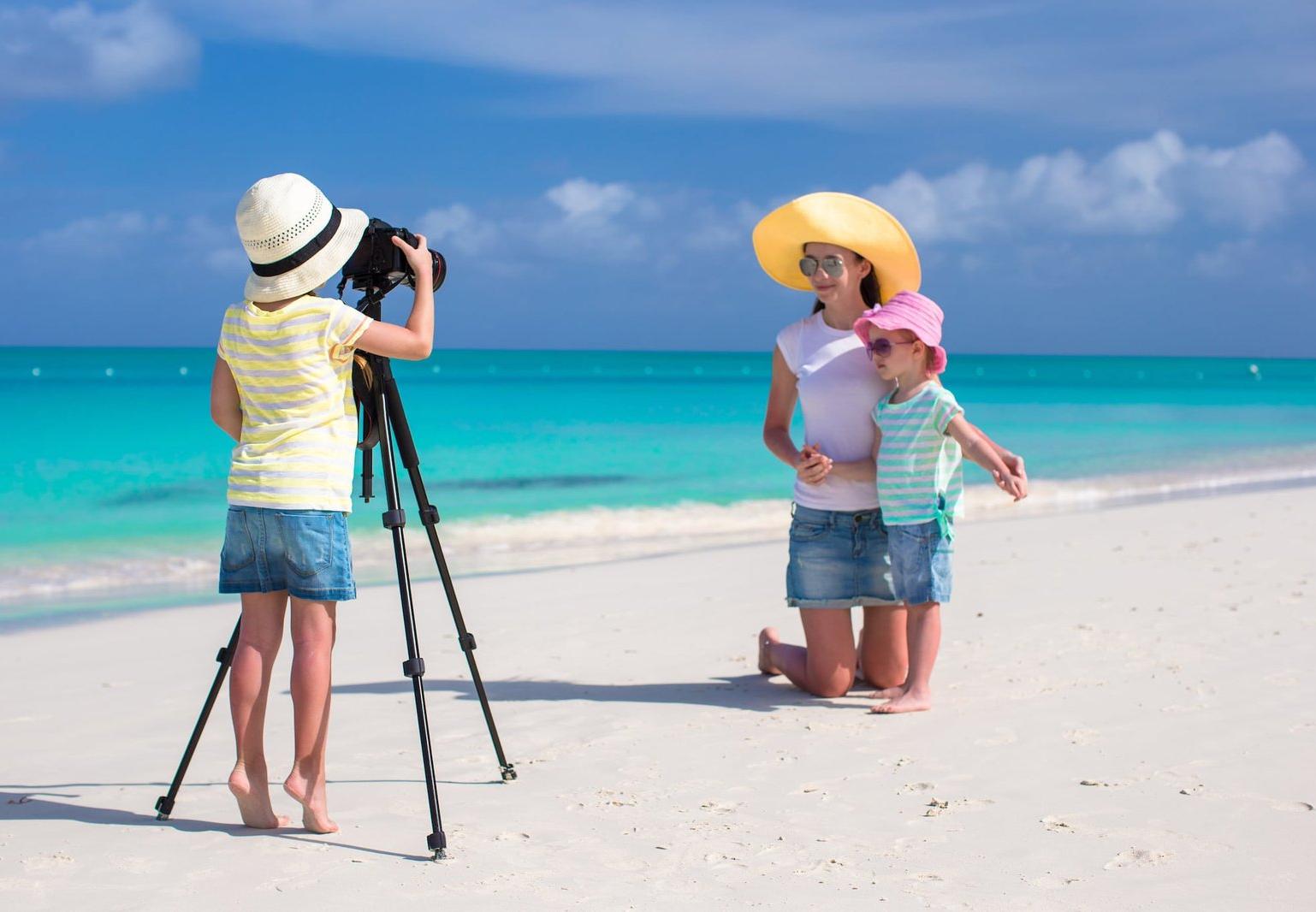 Family taking photos on tropical beach with turquoise water, Maldives