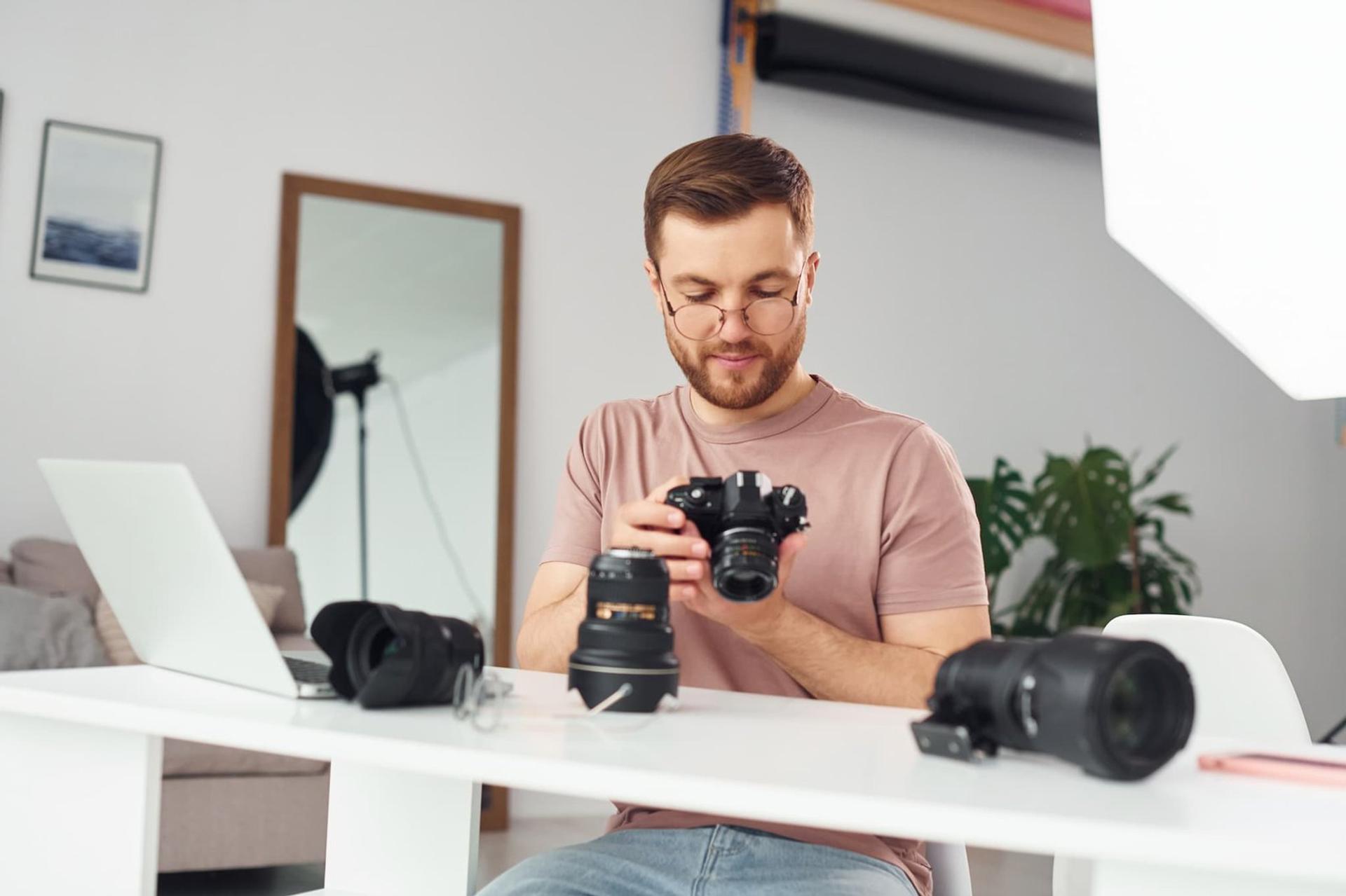 Photographer reviewing camera equipment at desk in home studio