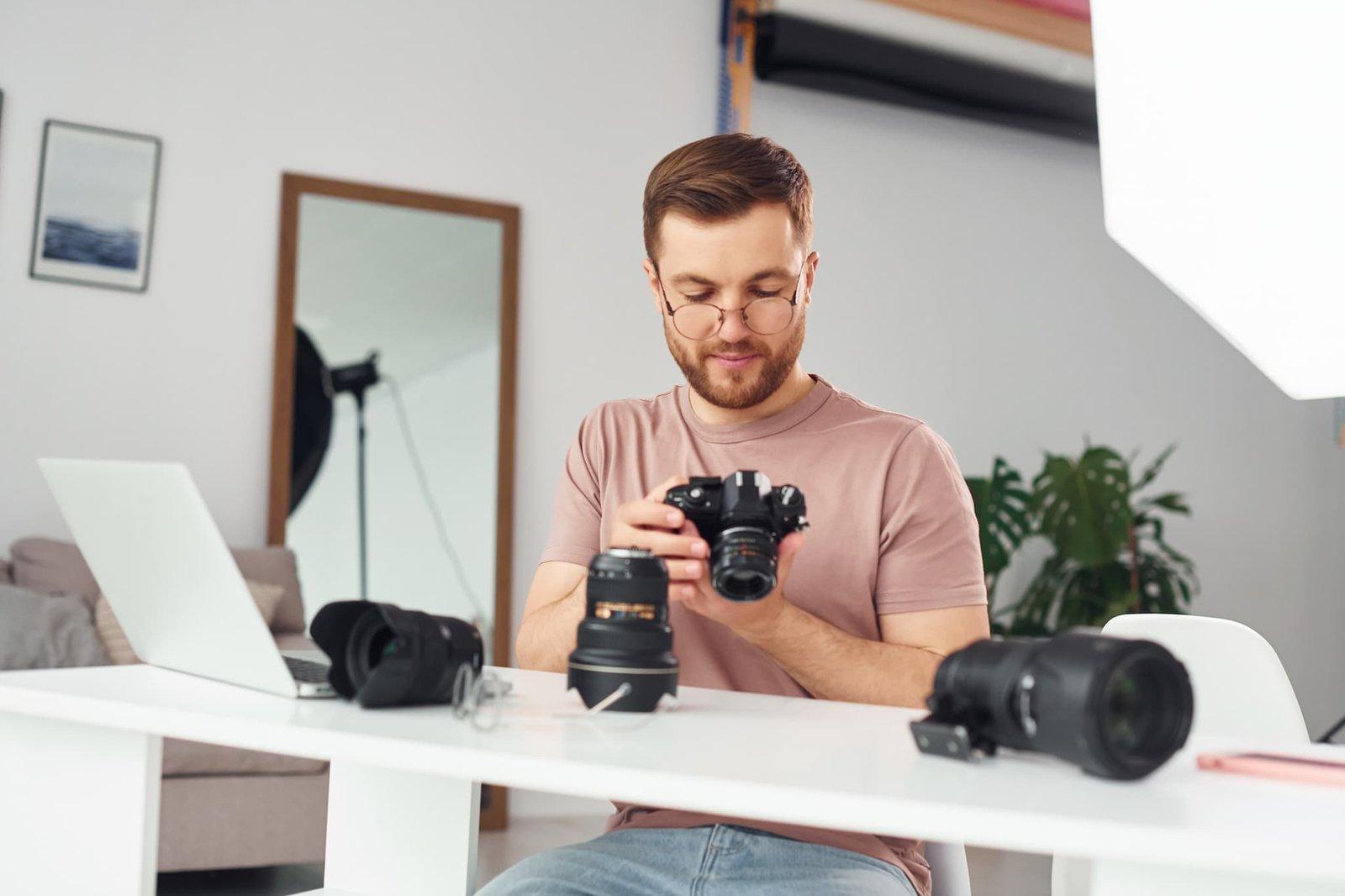 Photographer reviewing camera equipment at desk in home studio