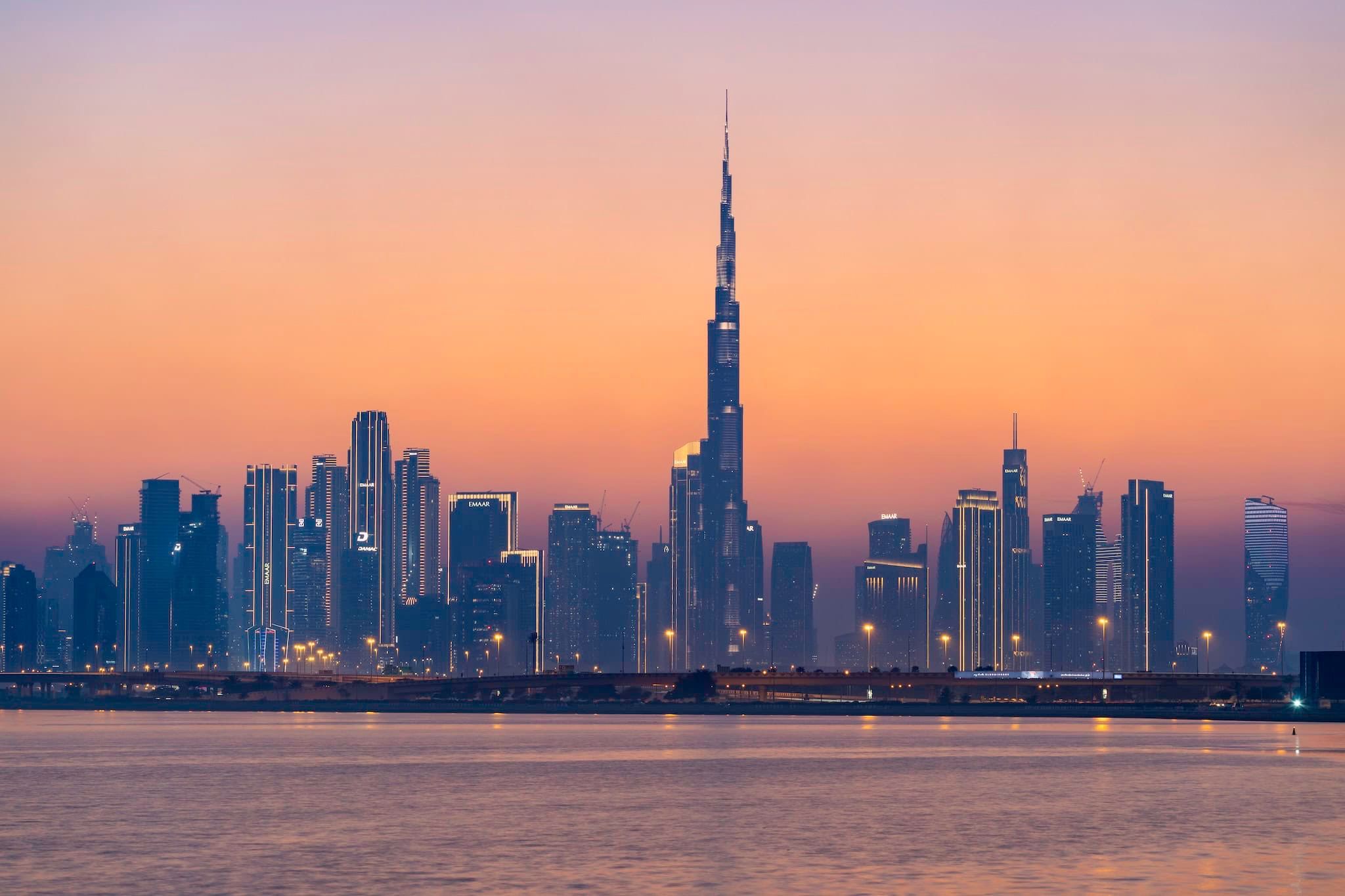 August: The skyline and Burj Khalifa across the water at sunset, Dubai, United Arab Emirates