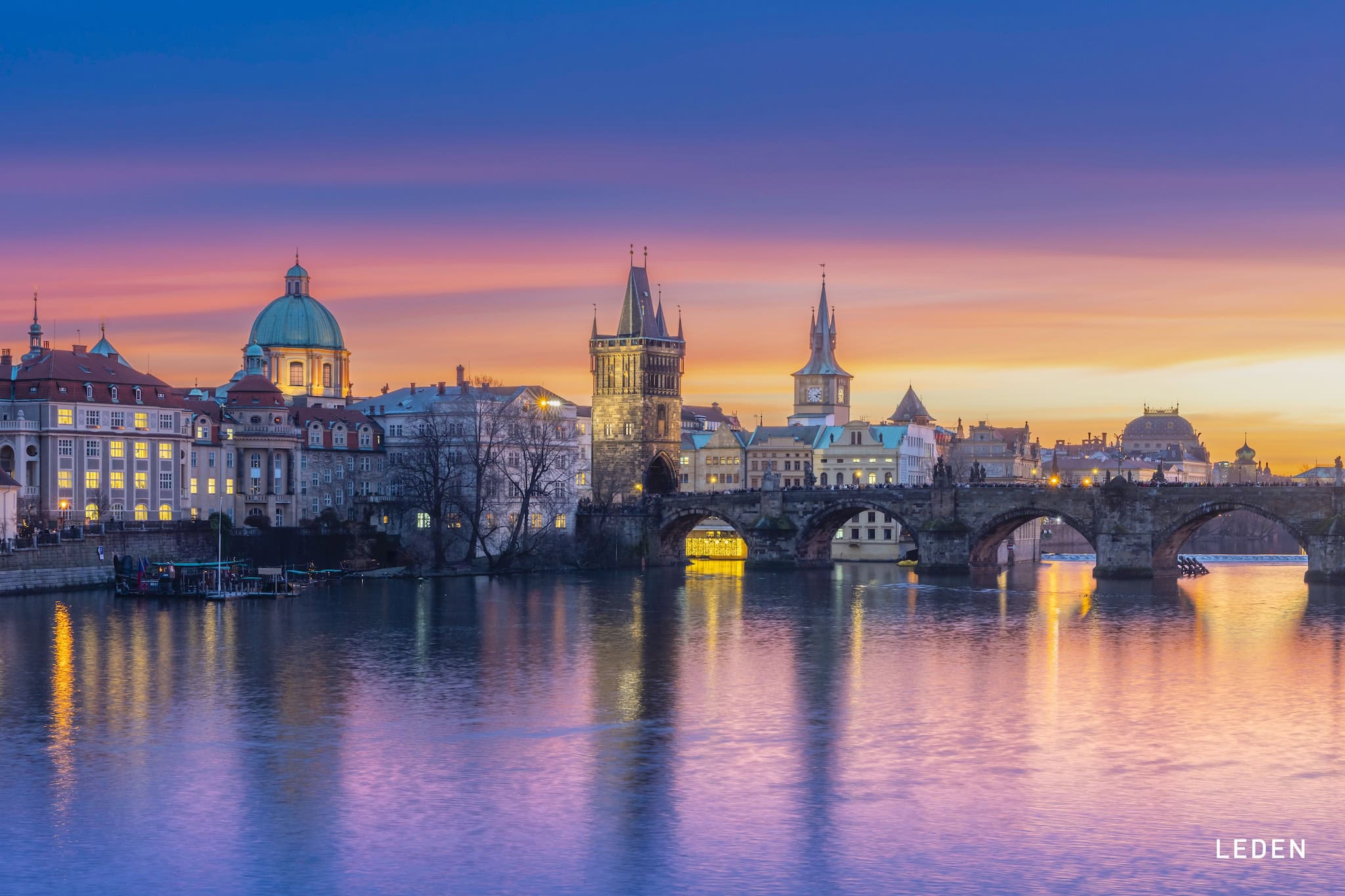 Leden: Karlův most a panorama Starého Města při západu slunce nad Vltavou, Praha