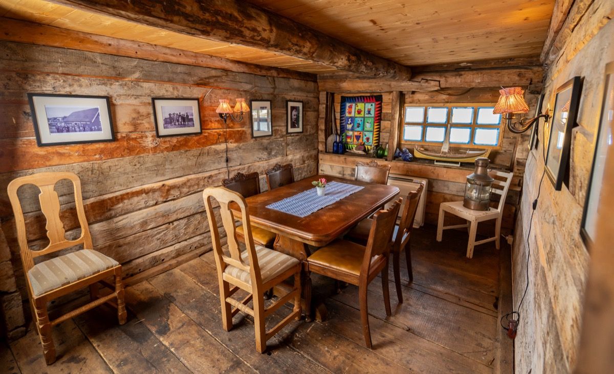 Rustikt rom med trevegger, antikke møbler, innrammet kunst og farget glass