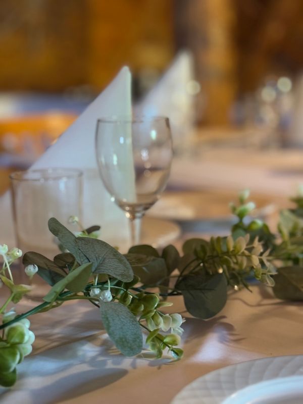 Detalj fra borddekking: vinglass, serviettbretting og grønneri